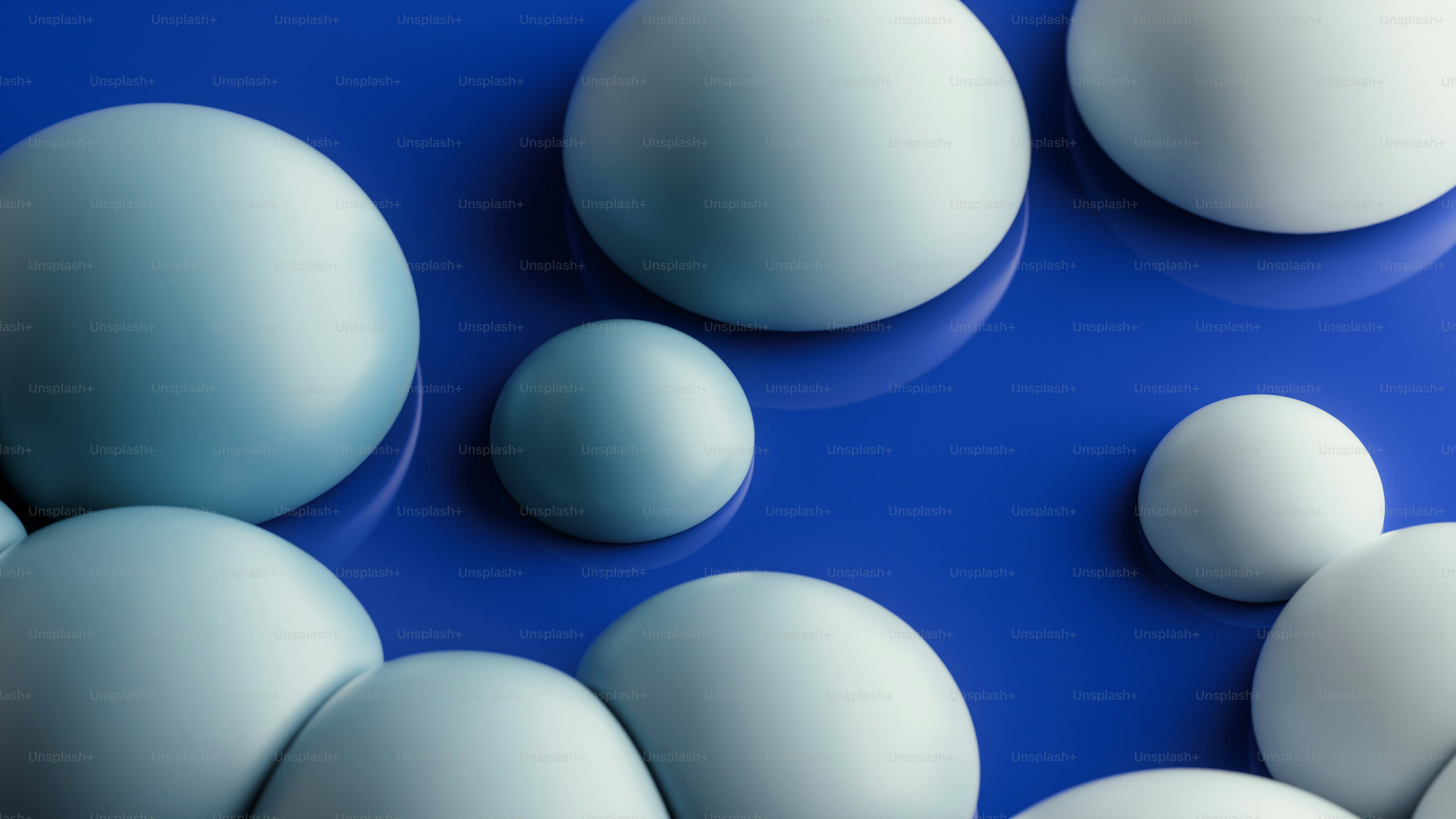 Smooth light blue spheres of varying sizes on a glossy dark blue surface
