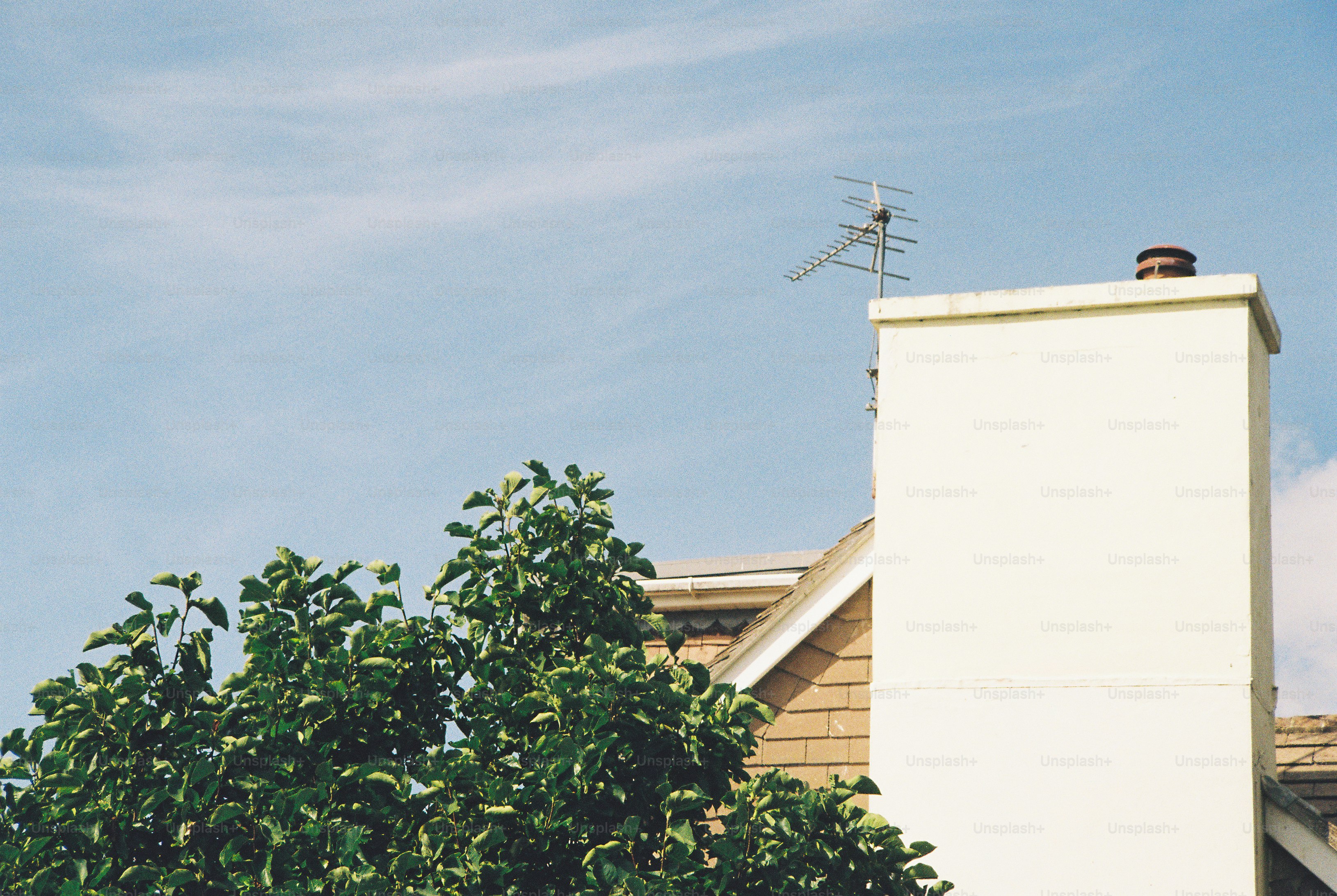 A white chimney with a television antenna against a clear blue sky