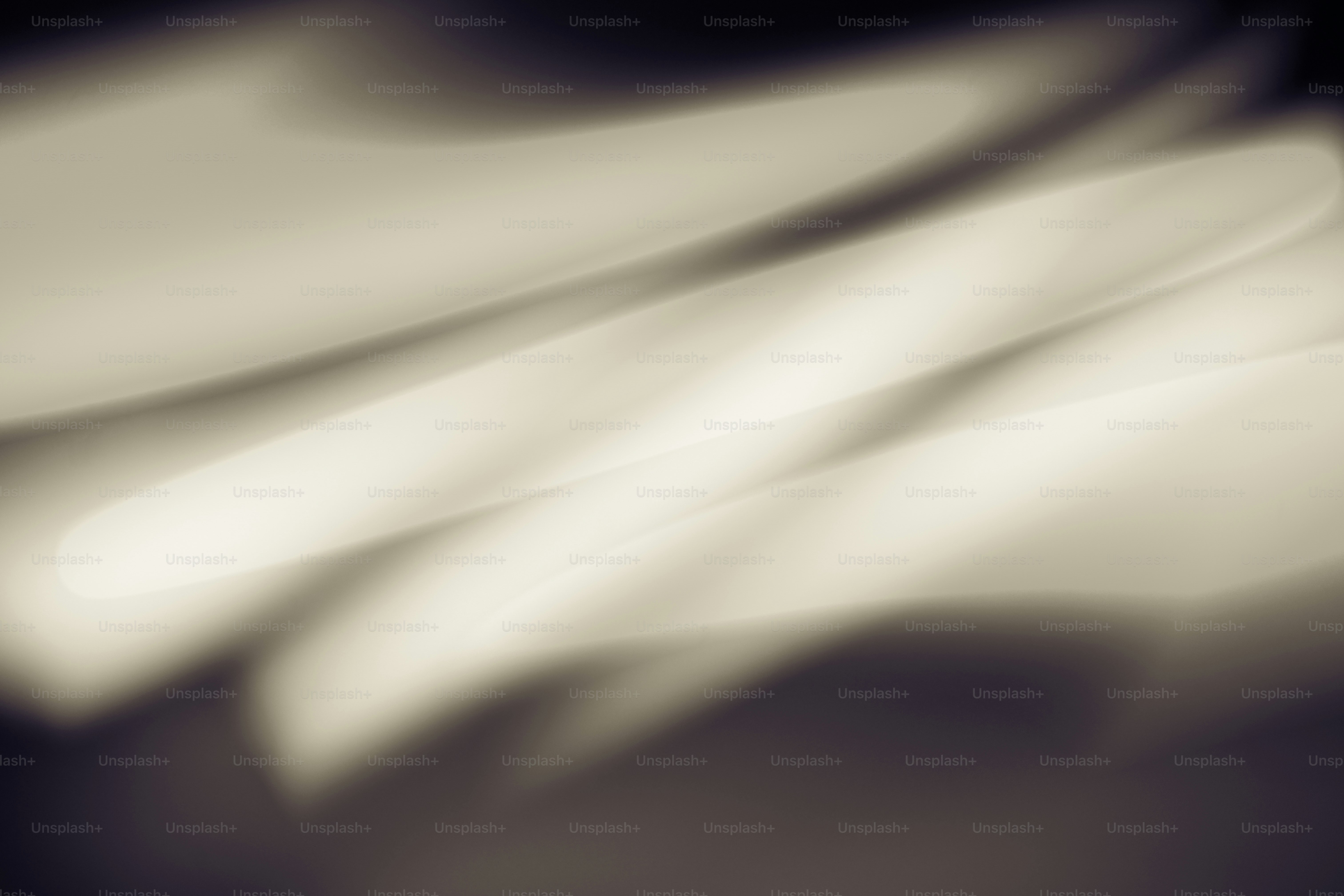 Abstract light streaks in soft white and grey tones across a dark background