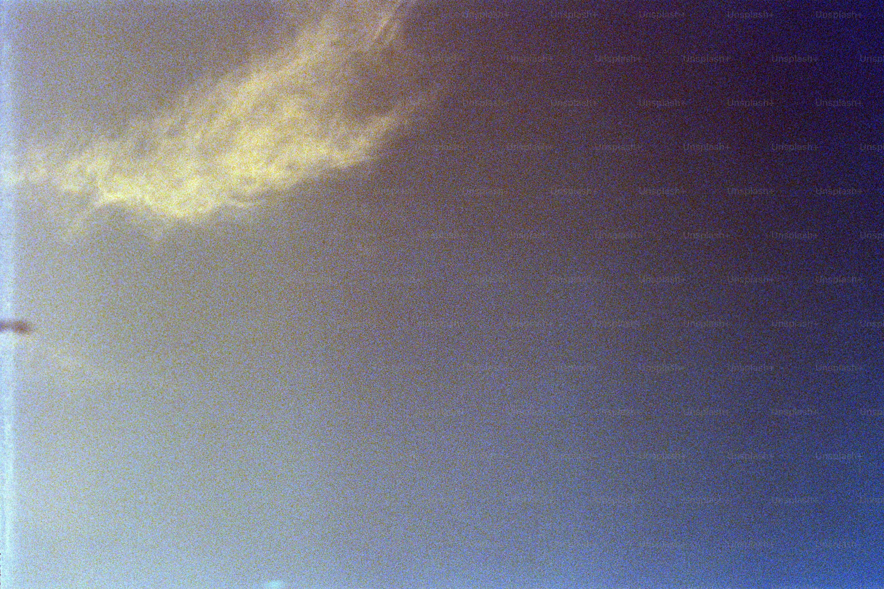 A wispy yellow cloud formation against a deep blue sky