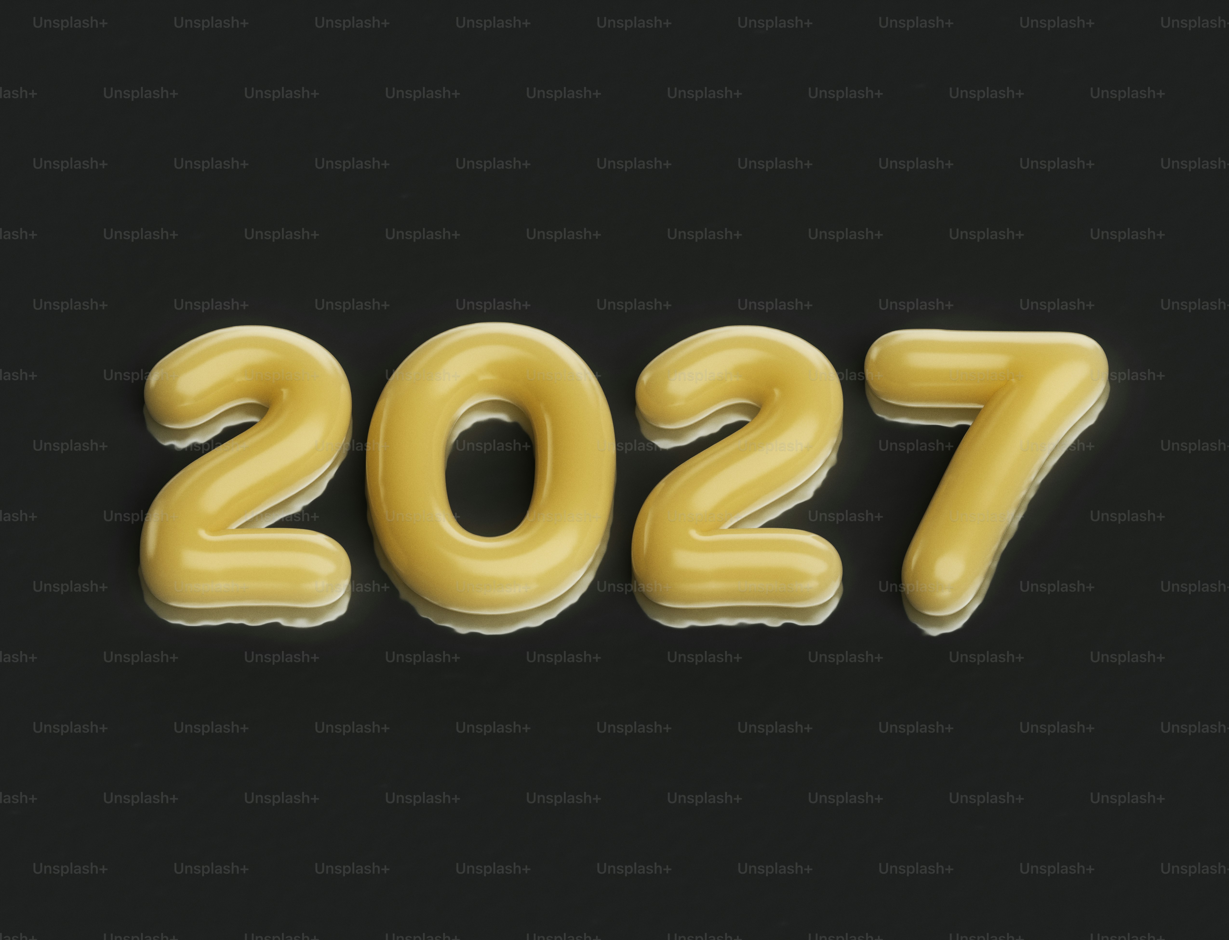 The number 2027 in glossy yellow balloon letters on a dark grey surface