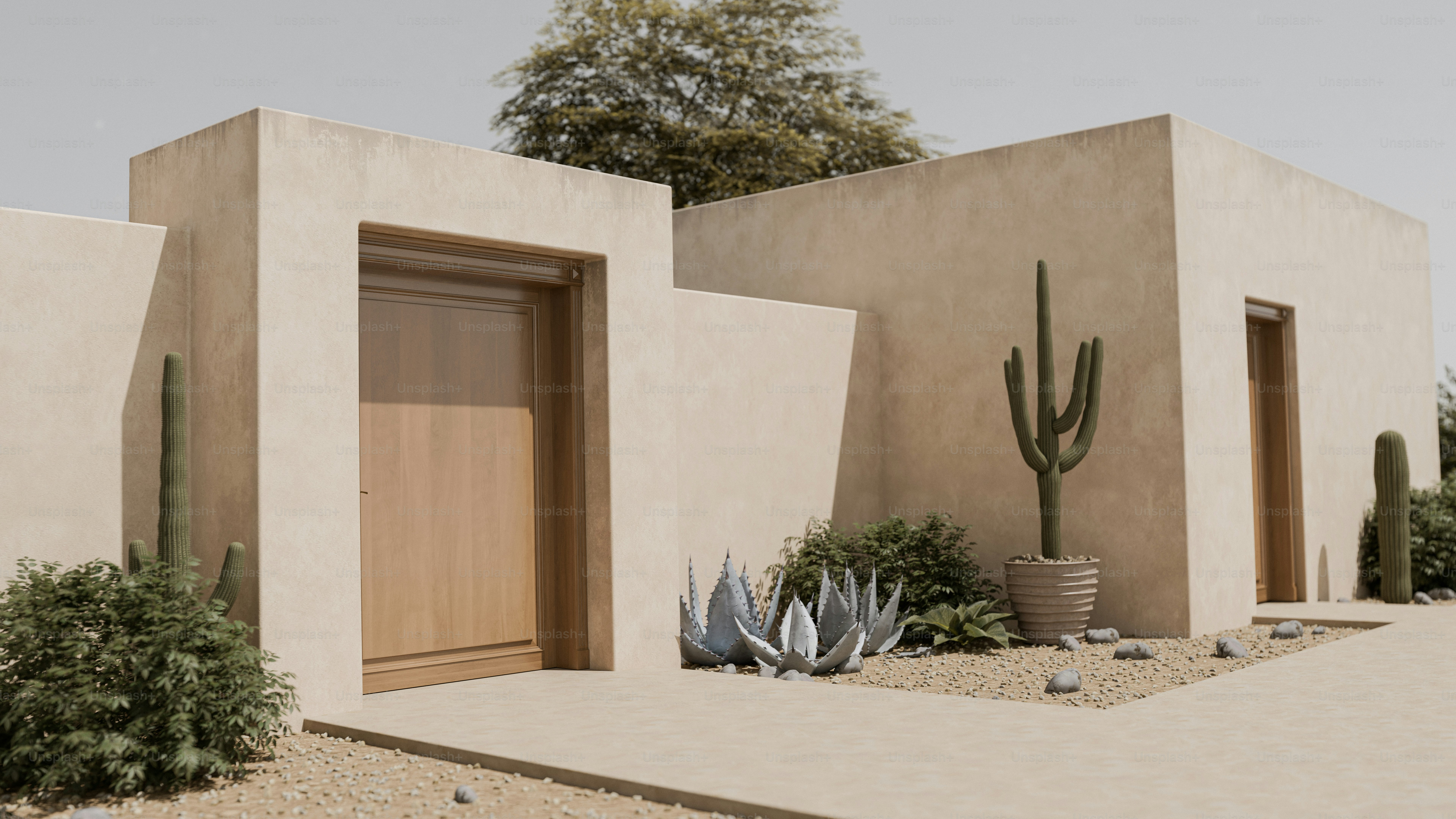 A beige stucco building with wooden doors and cacti in a desert garden