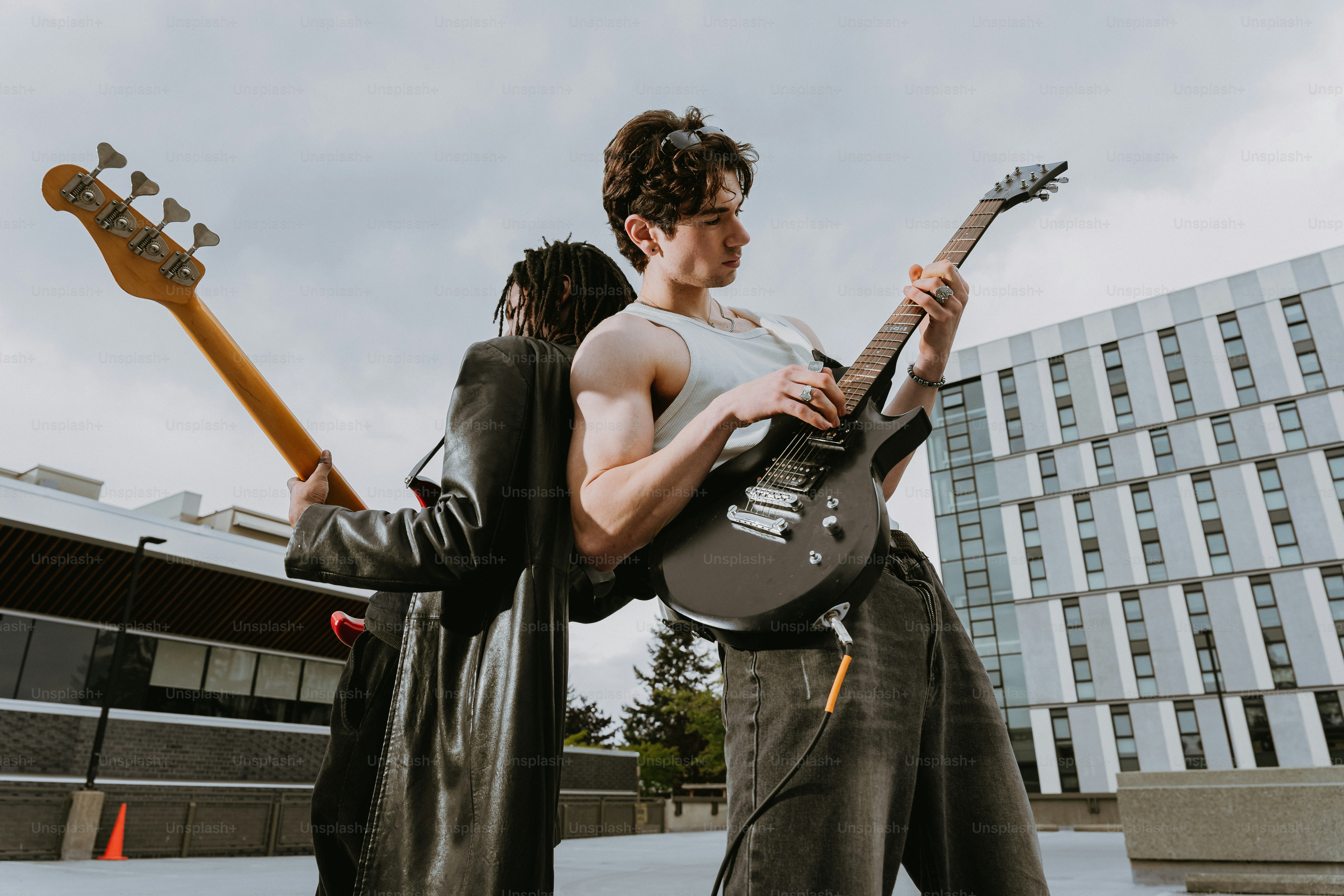 Due musicisti che suonano chitarra elettrica e basso uno dietro all'altro all'aperto