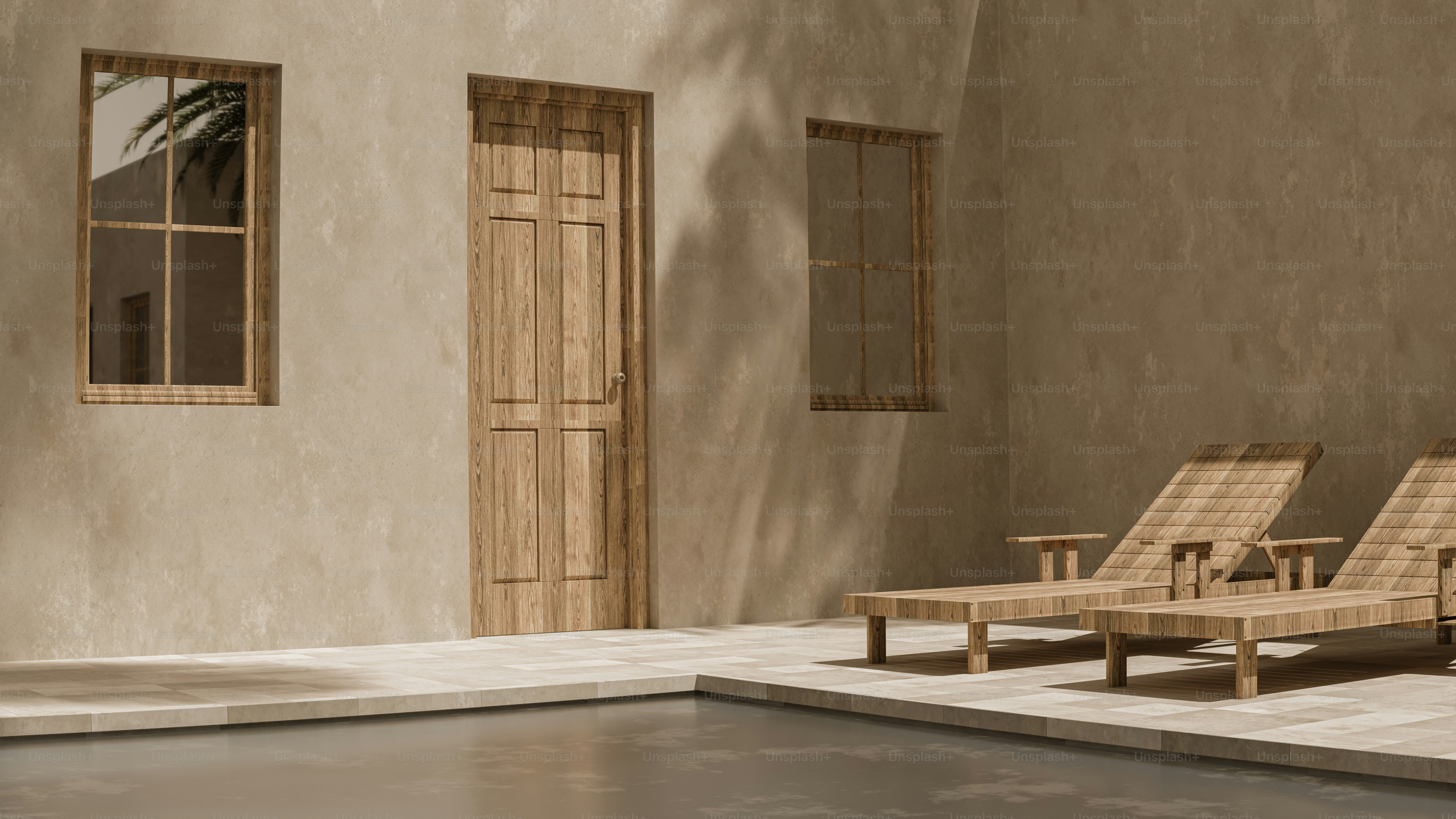 Two wooden lounge chairs beside a pool near a beige wall with windows