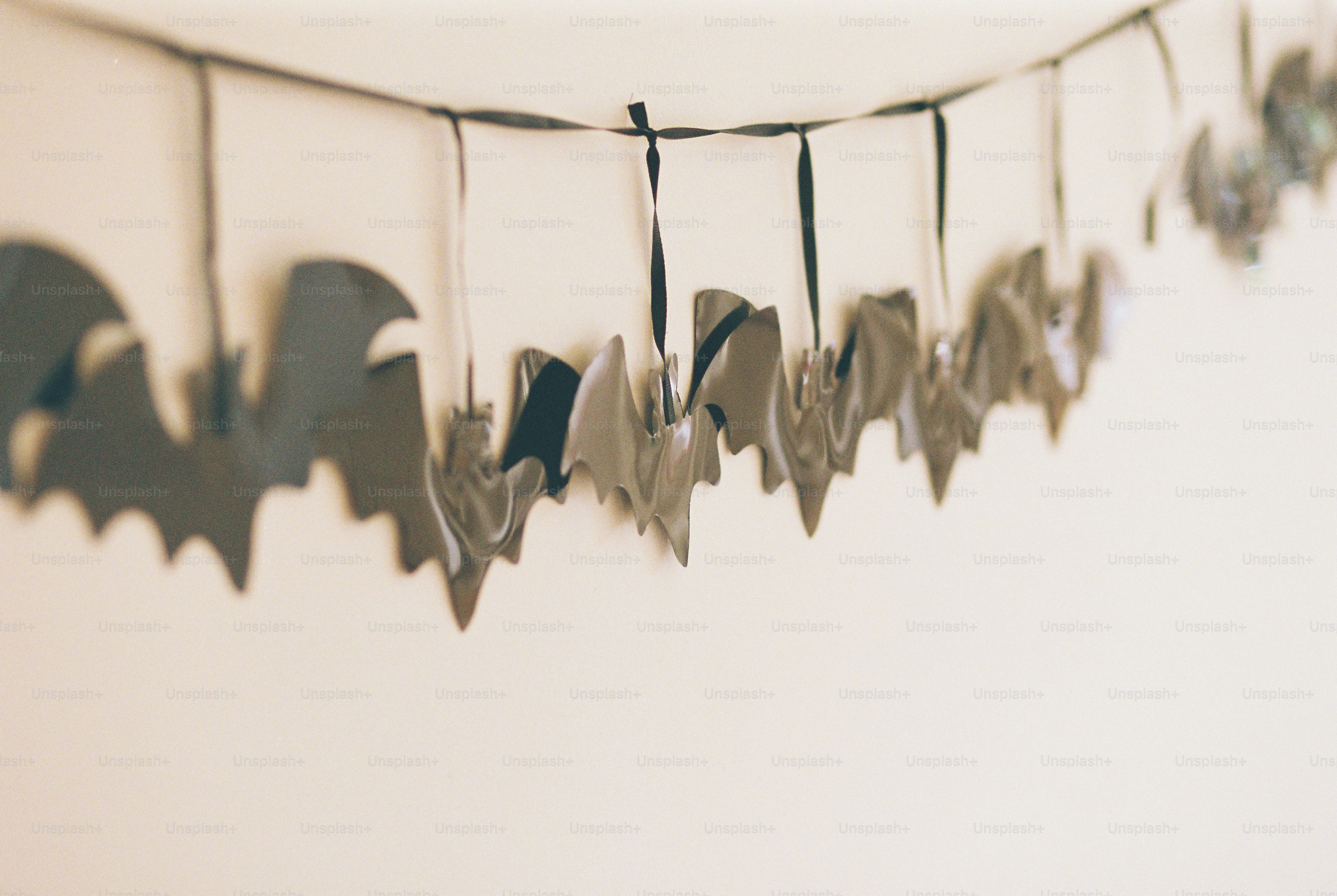 A paper bat garland on dark ribbon against a plain wall