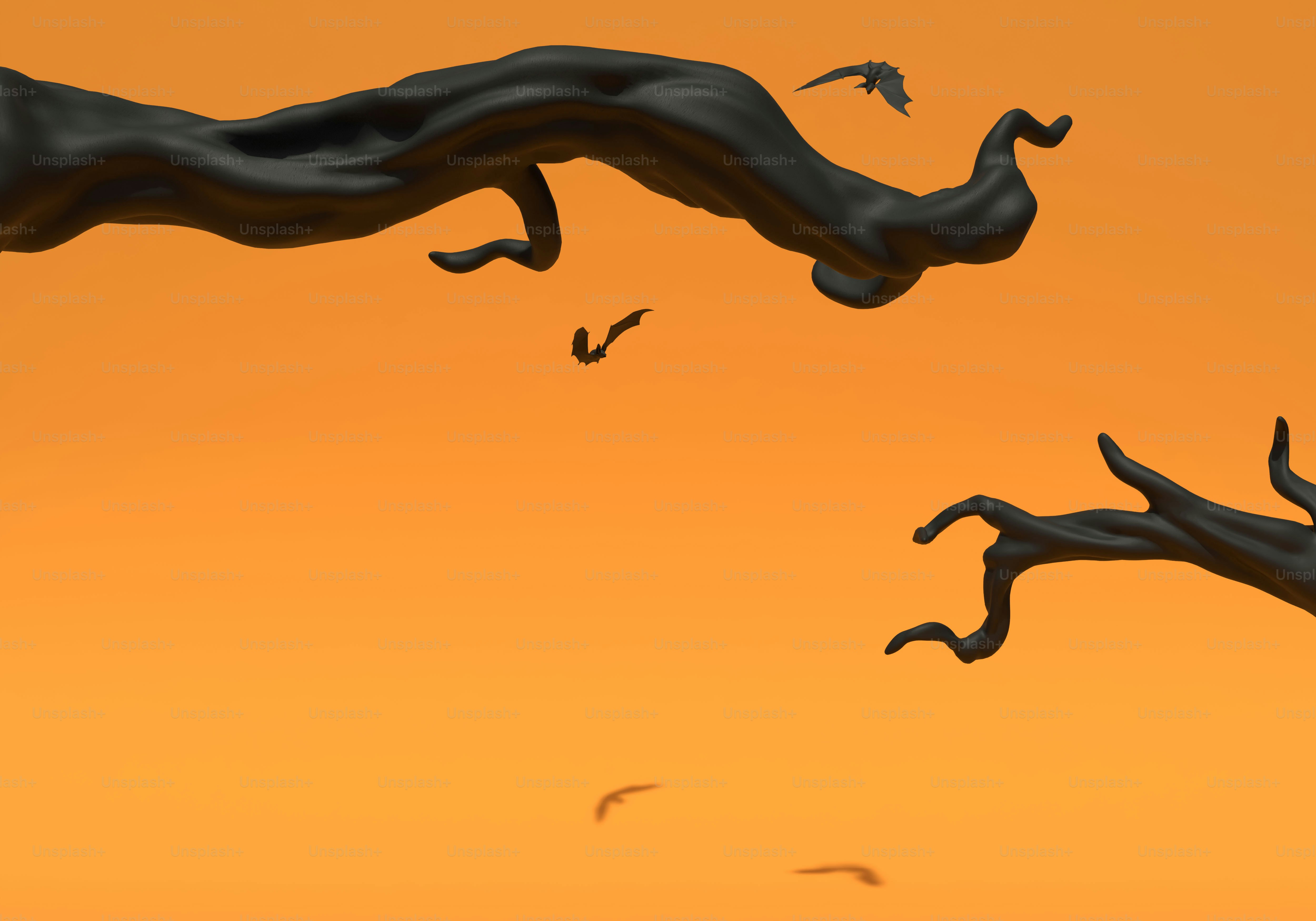 Black tree branches and silhouettes of bats against a solid orange background