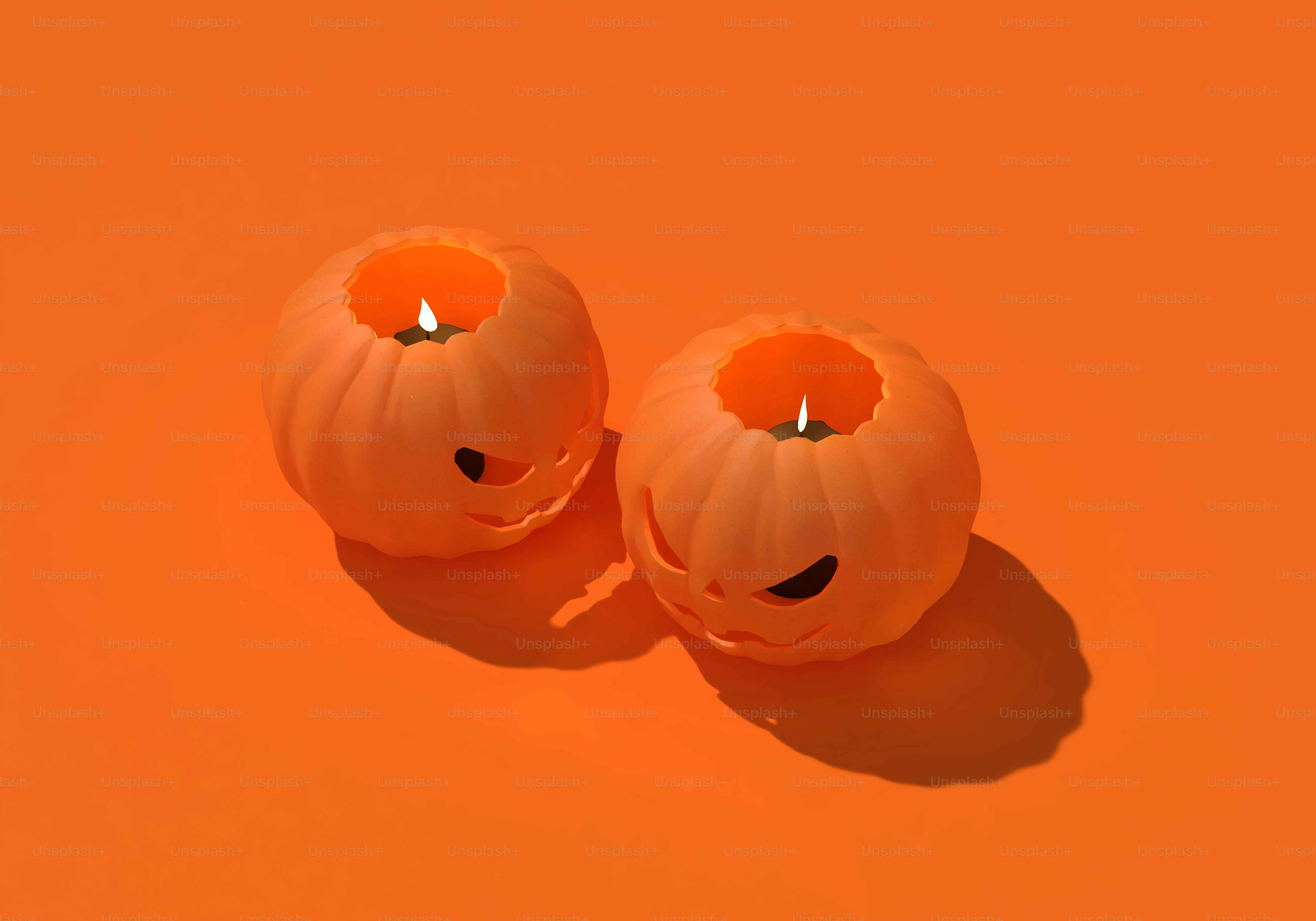 Two orange pumpkin candle holders with carved faces on an orange background