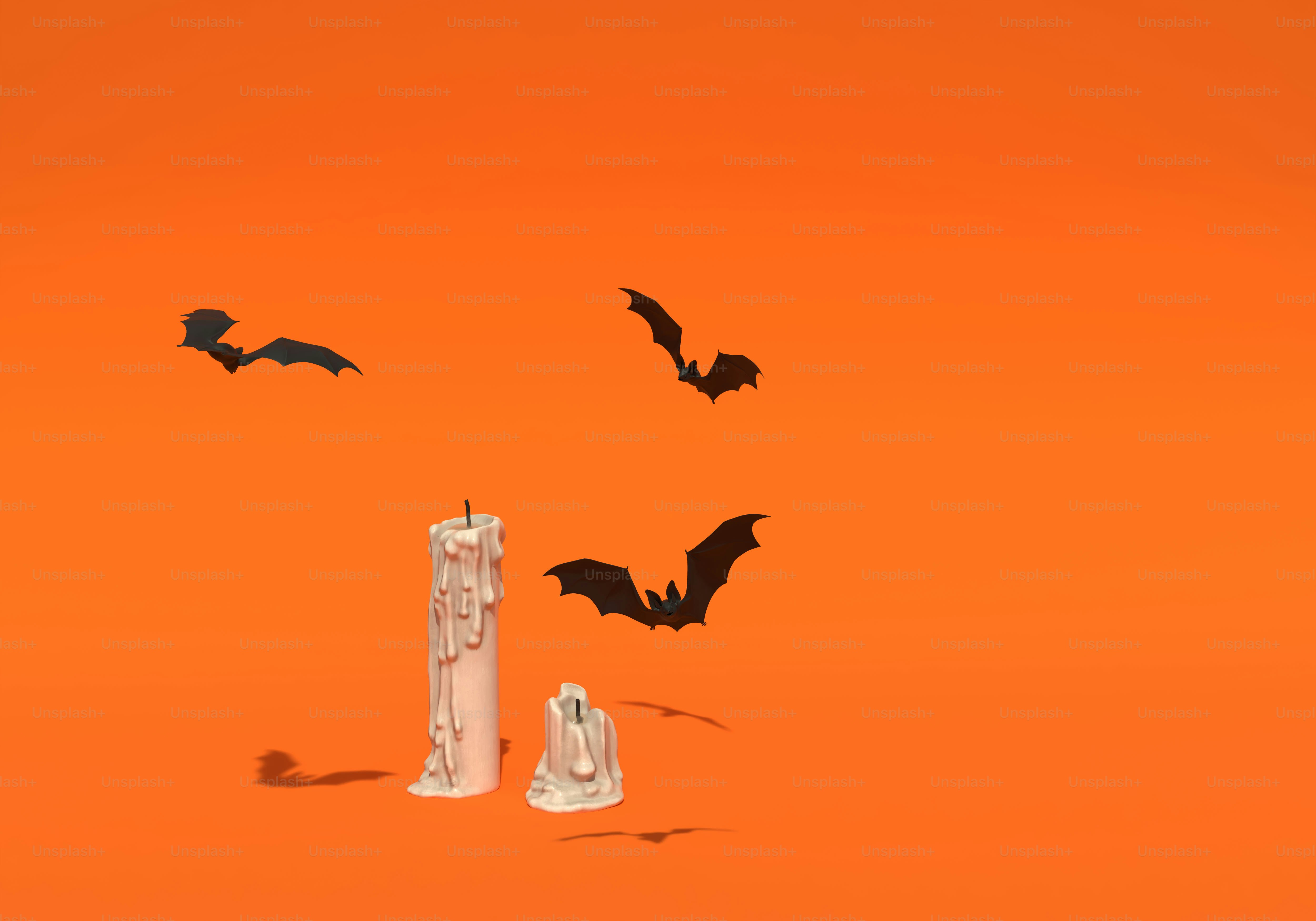 Three black bats flying above two melting white candles on an orange background