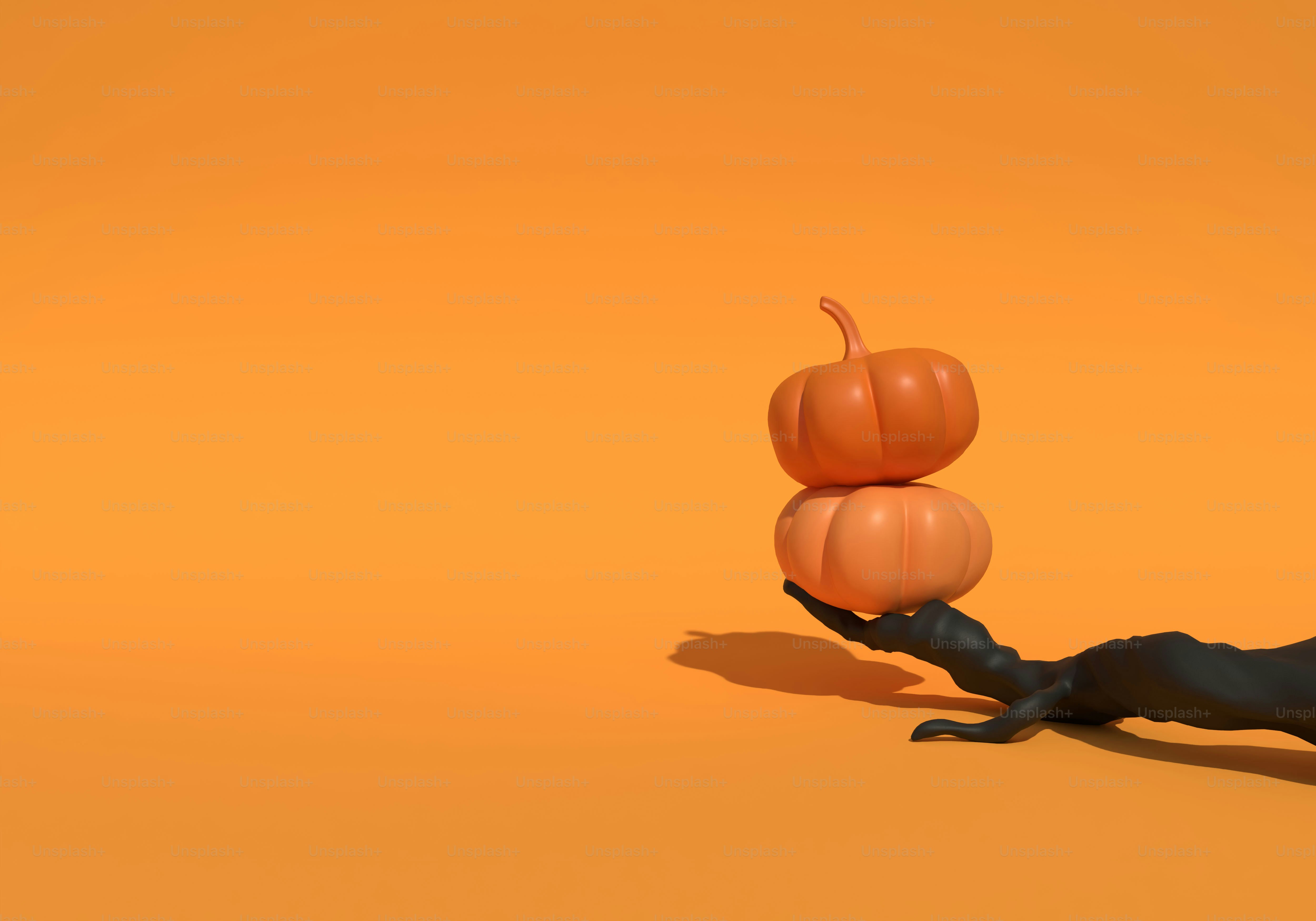 Two stacked orange pumpkins balanced on a black tree branch against an orange background