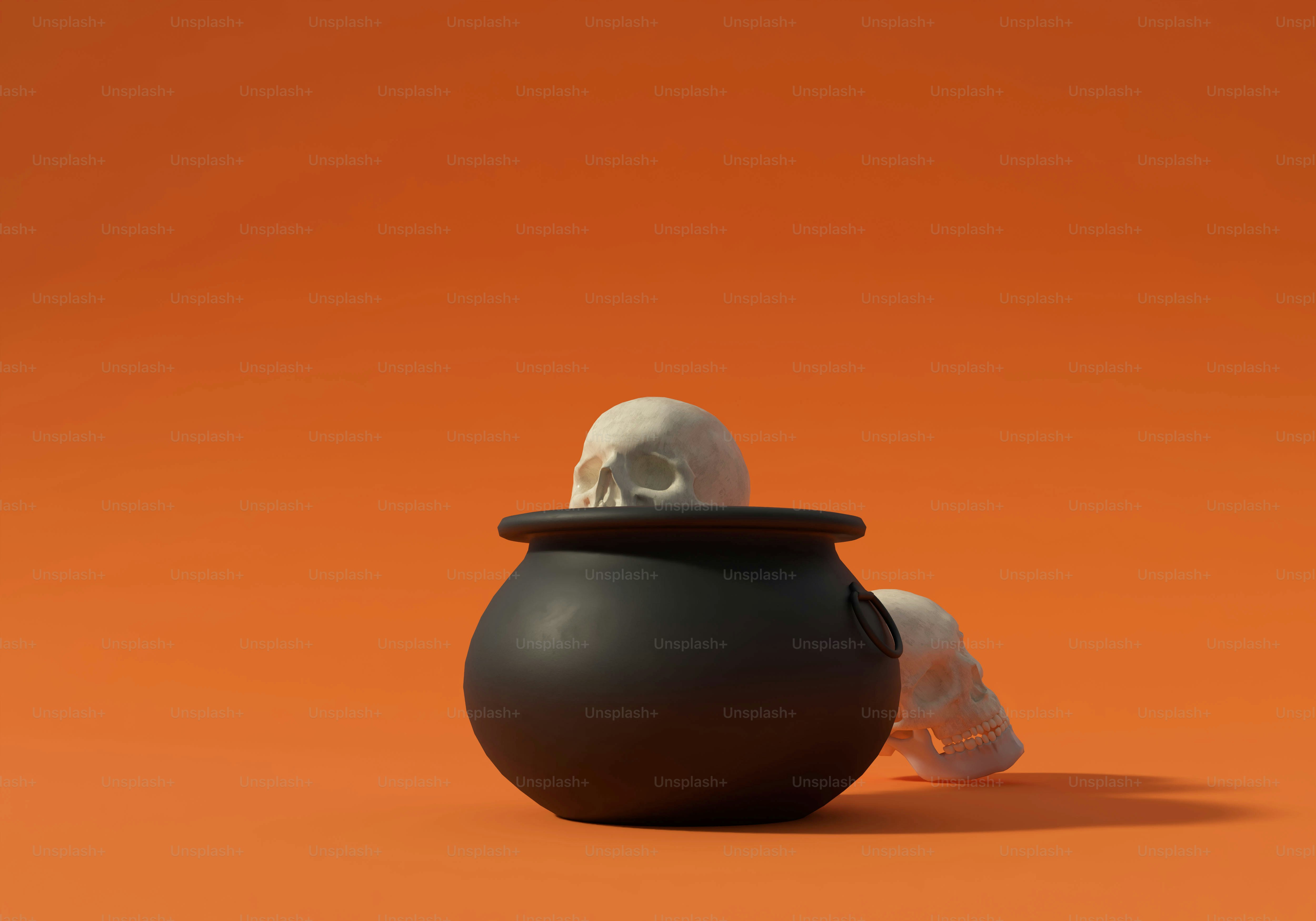 Two human skulls with one inside a black cauldron on an orange background