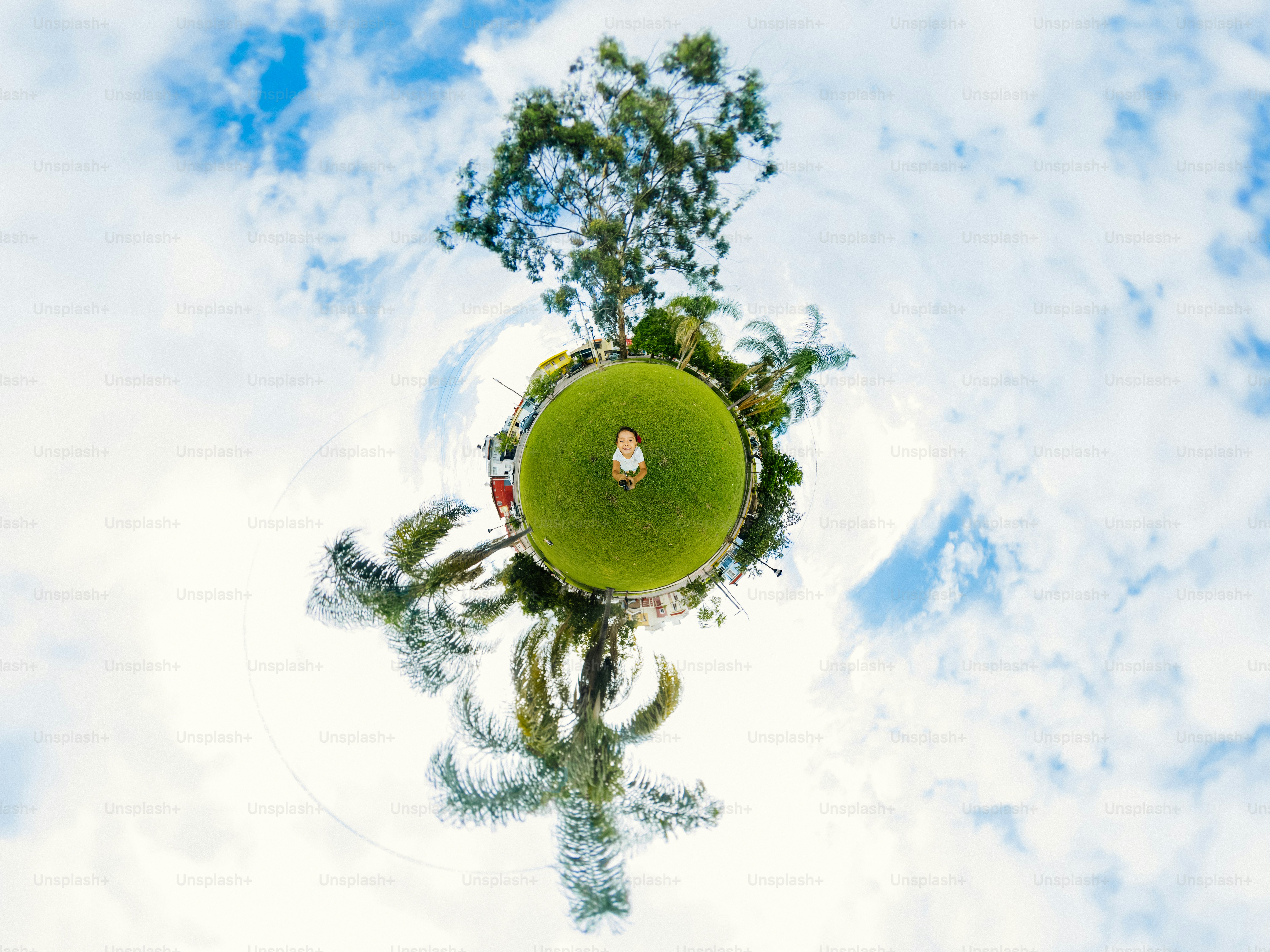 A child standing on a small green planet with palm trees and blue sky