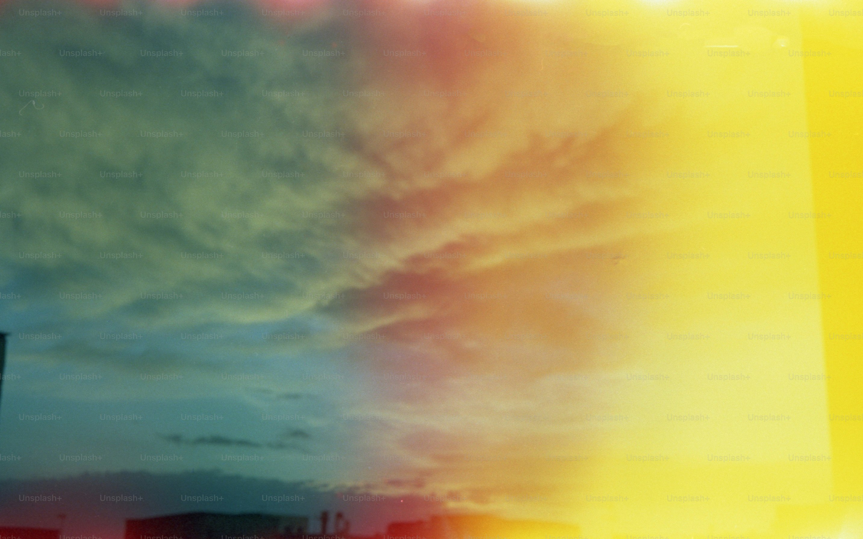 Clouds in a sky transitioning from blue to a bright yellow light leak