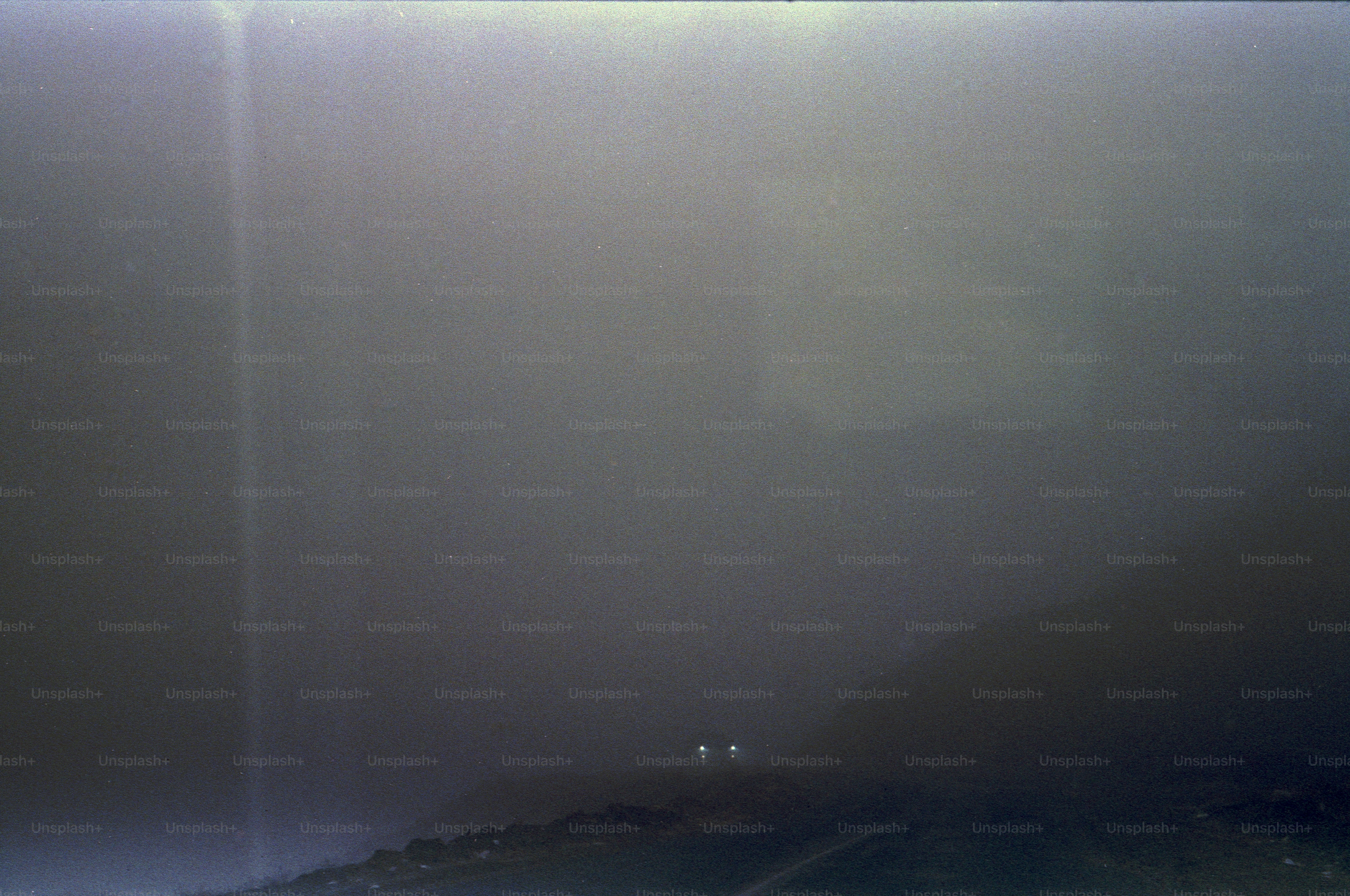Two distant lights glowing in a dark and misty landscape