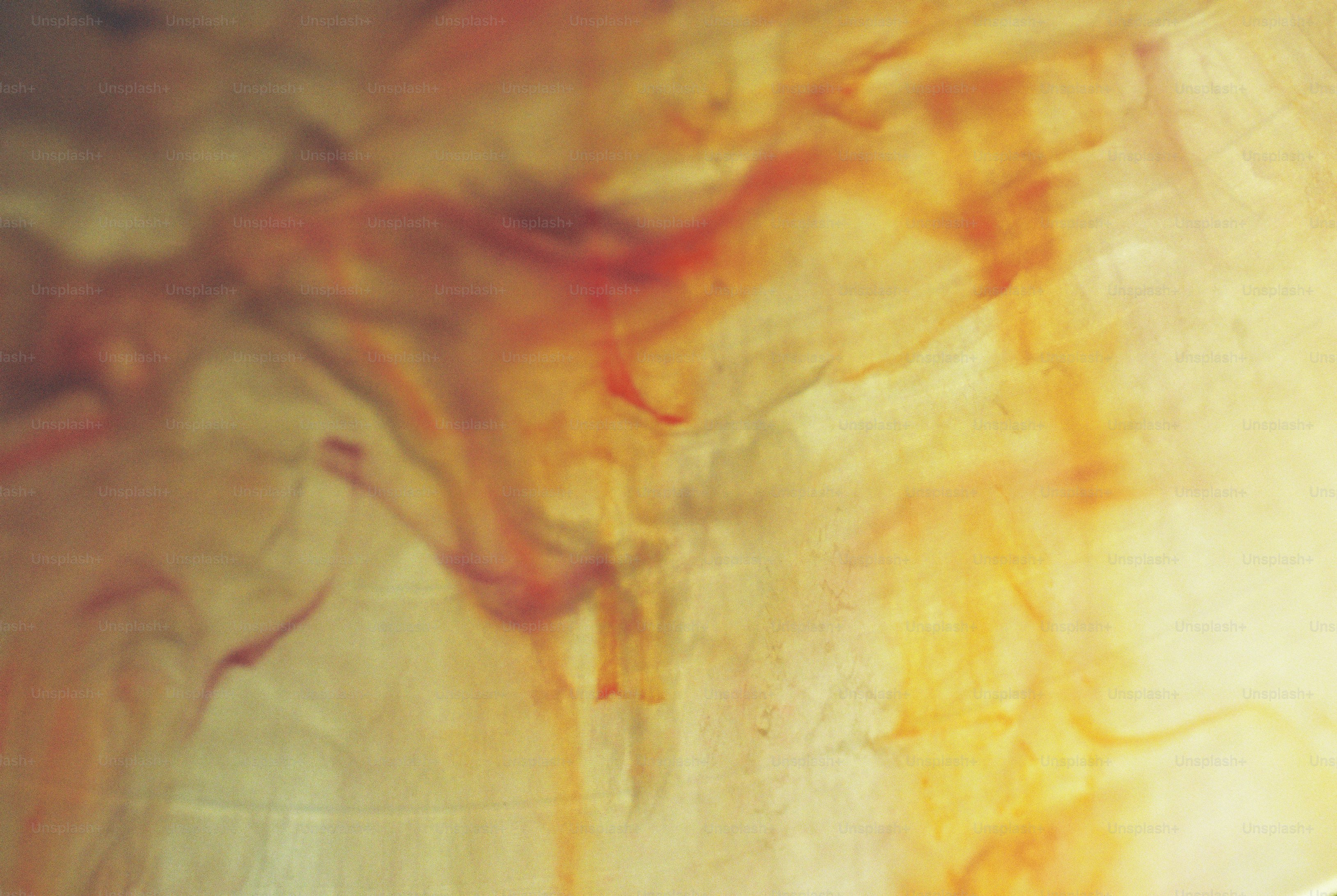 Amber and red wispy patterns diffusing through a pale translucent surface