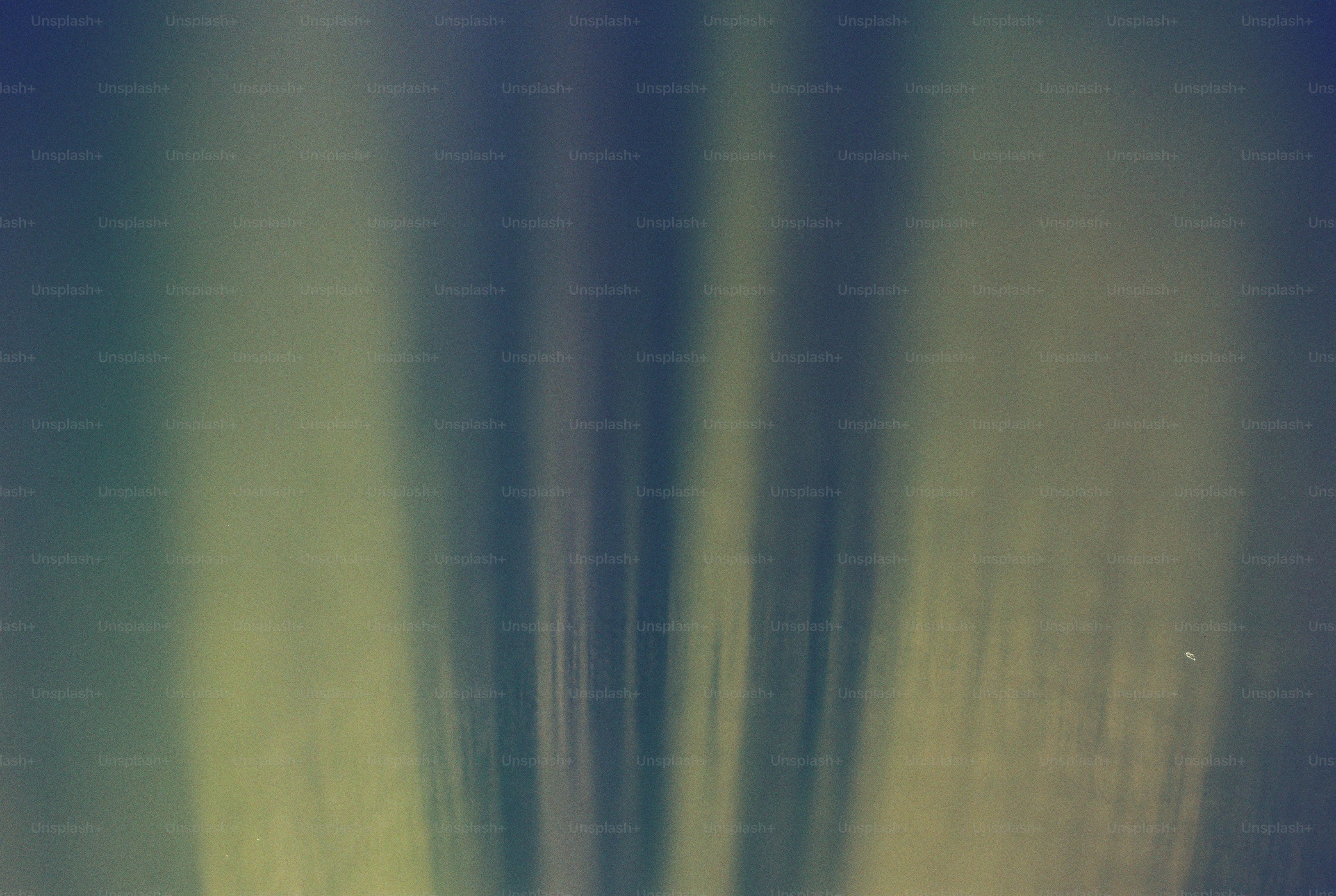 Vertical streaks of soft green and dark blue light in an abstract gradient