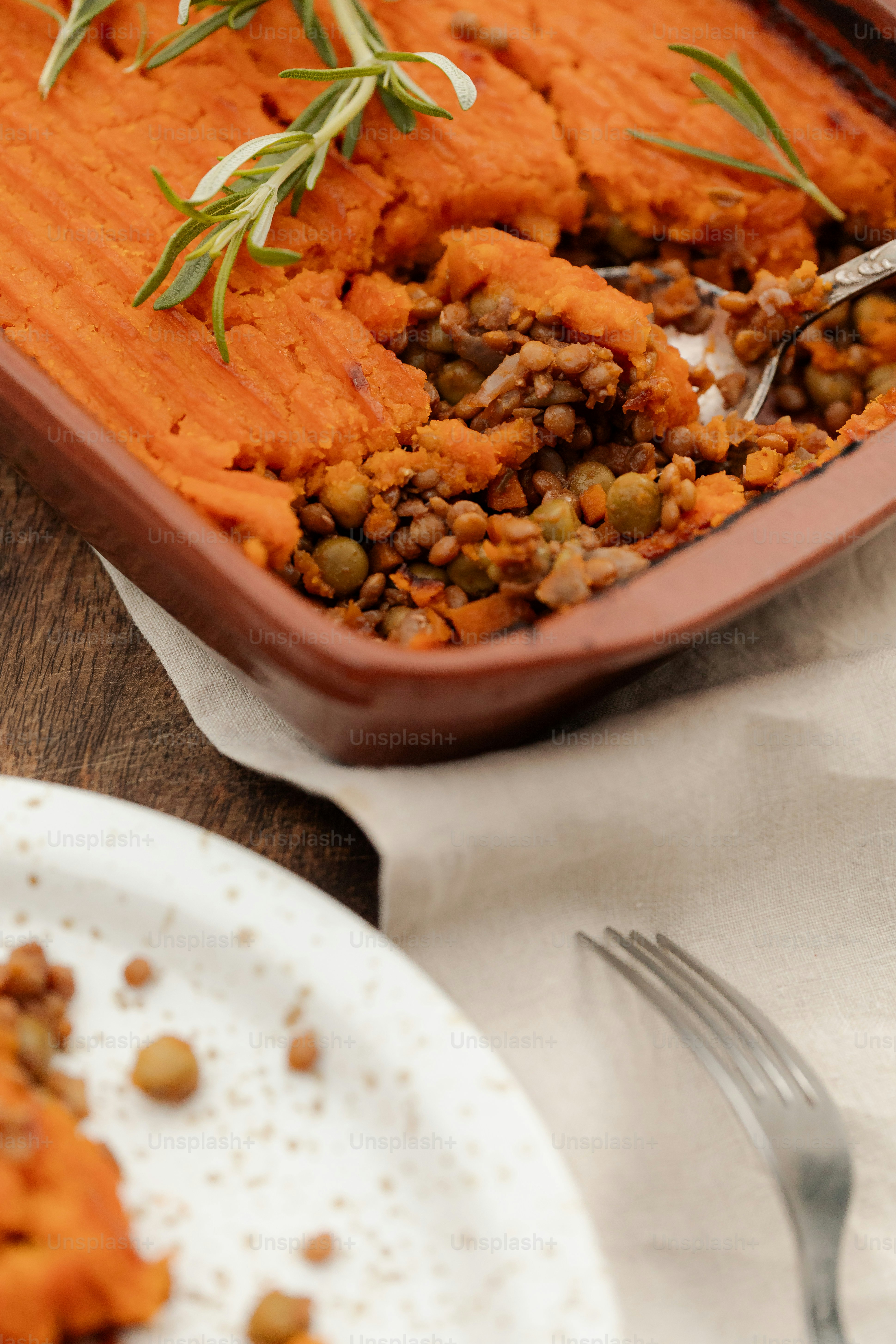 A shepherd's pie with a sweet potato topping and rosemary on a wooden table