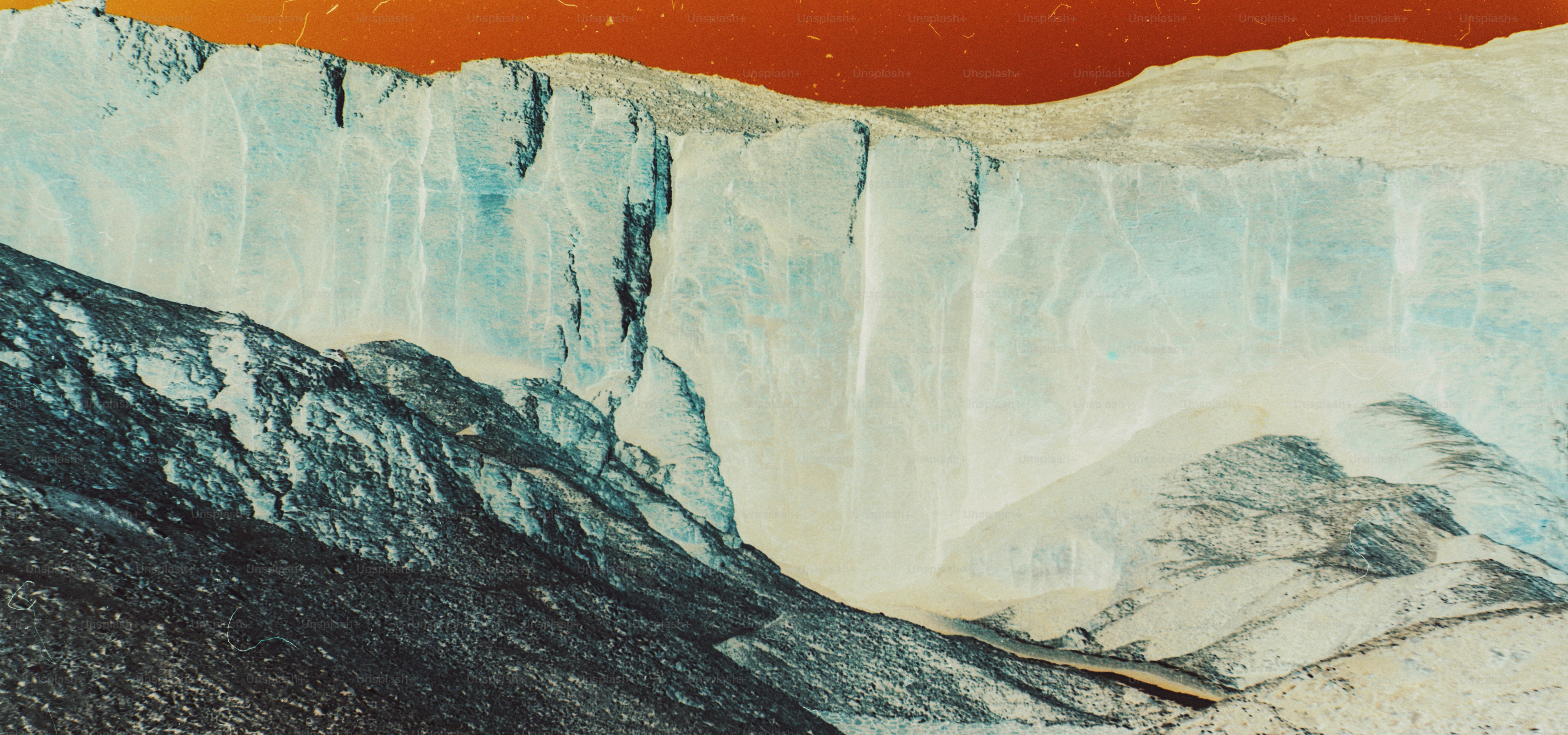 A steep blue glacier wall rising above dark rocky terrain under a red sky