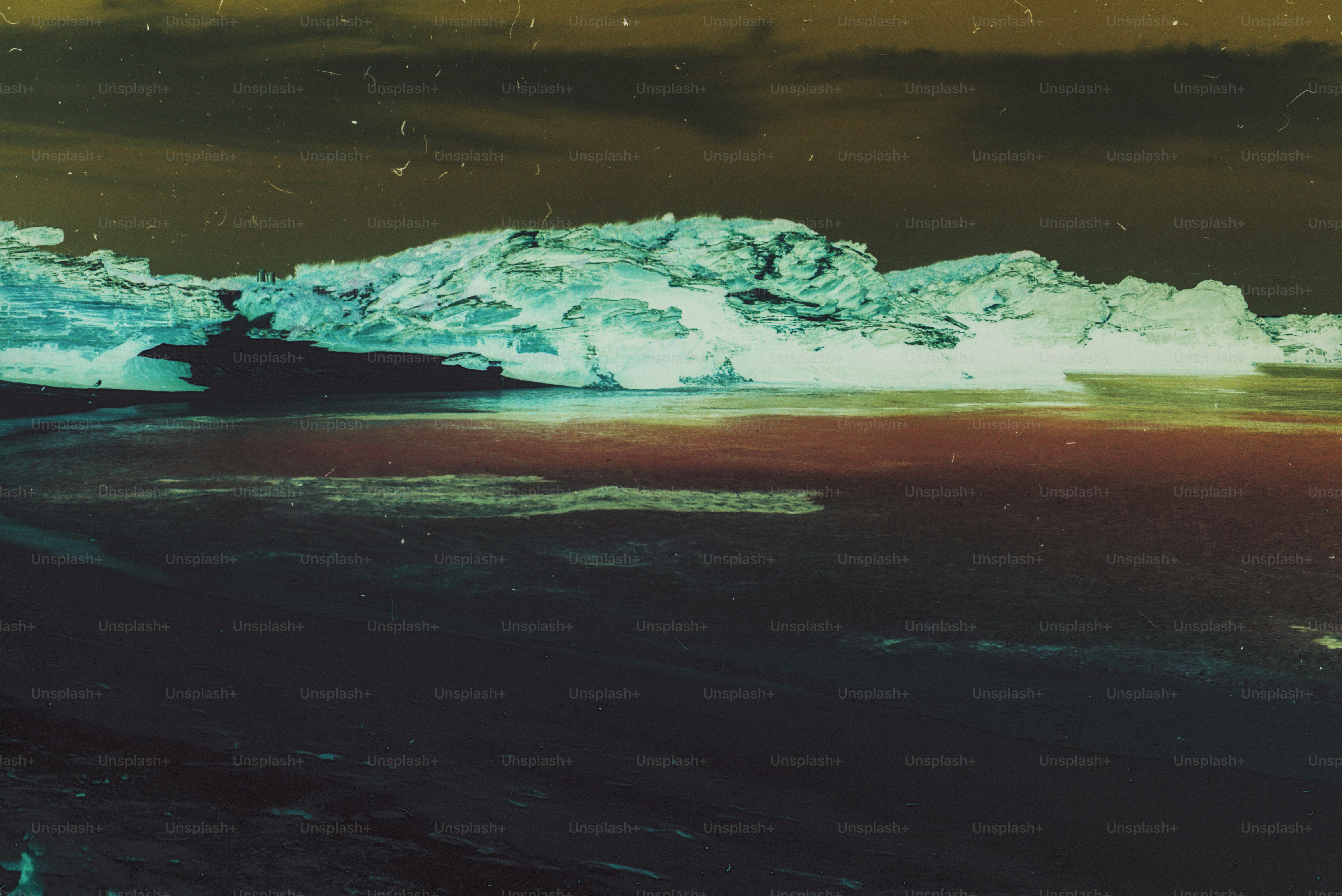 Inverted colors of a rocky coastline with dark sand and a pale cliff