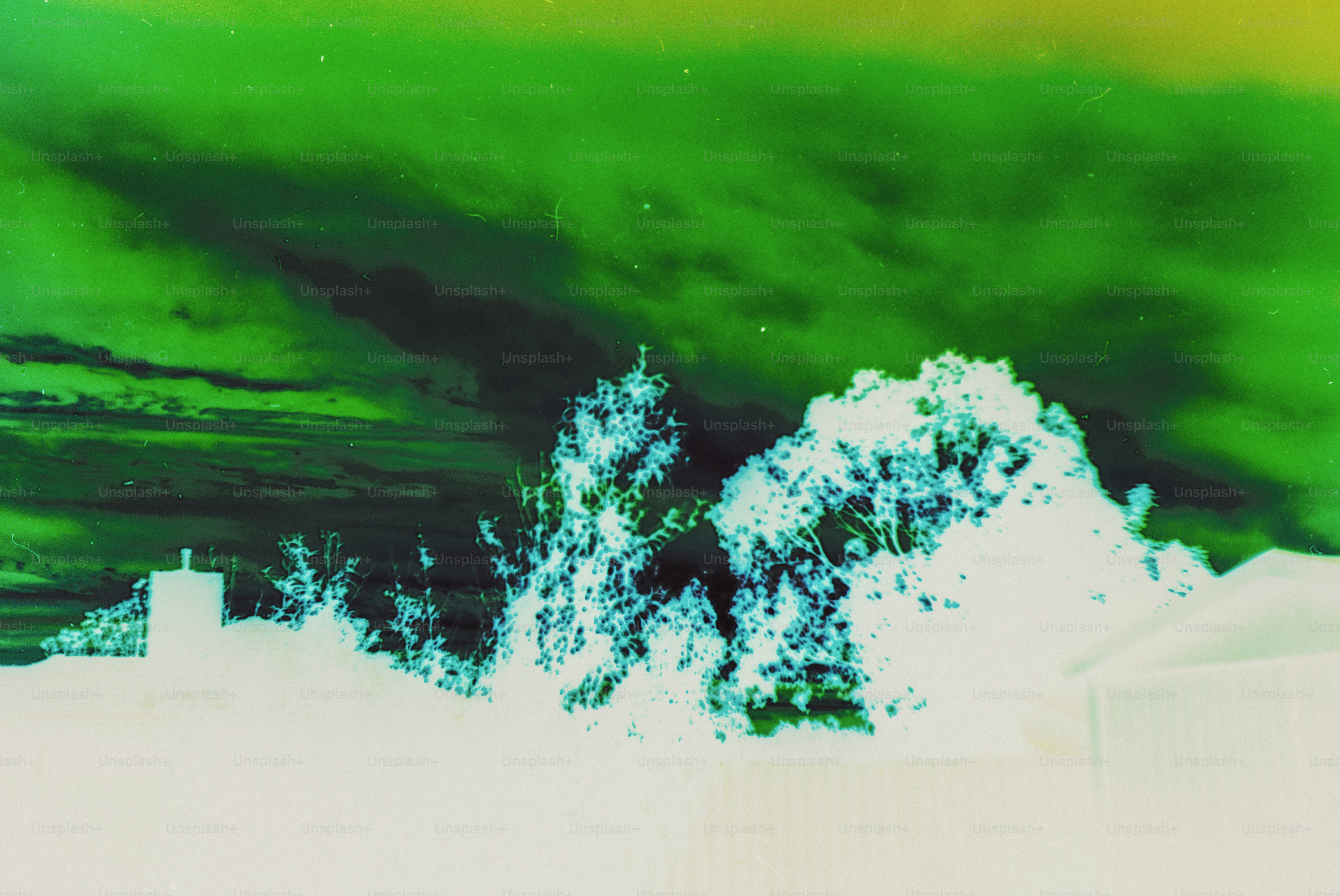 Inverted silhouette of trees and a chimney against a vibrant green sky