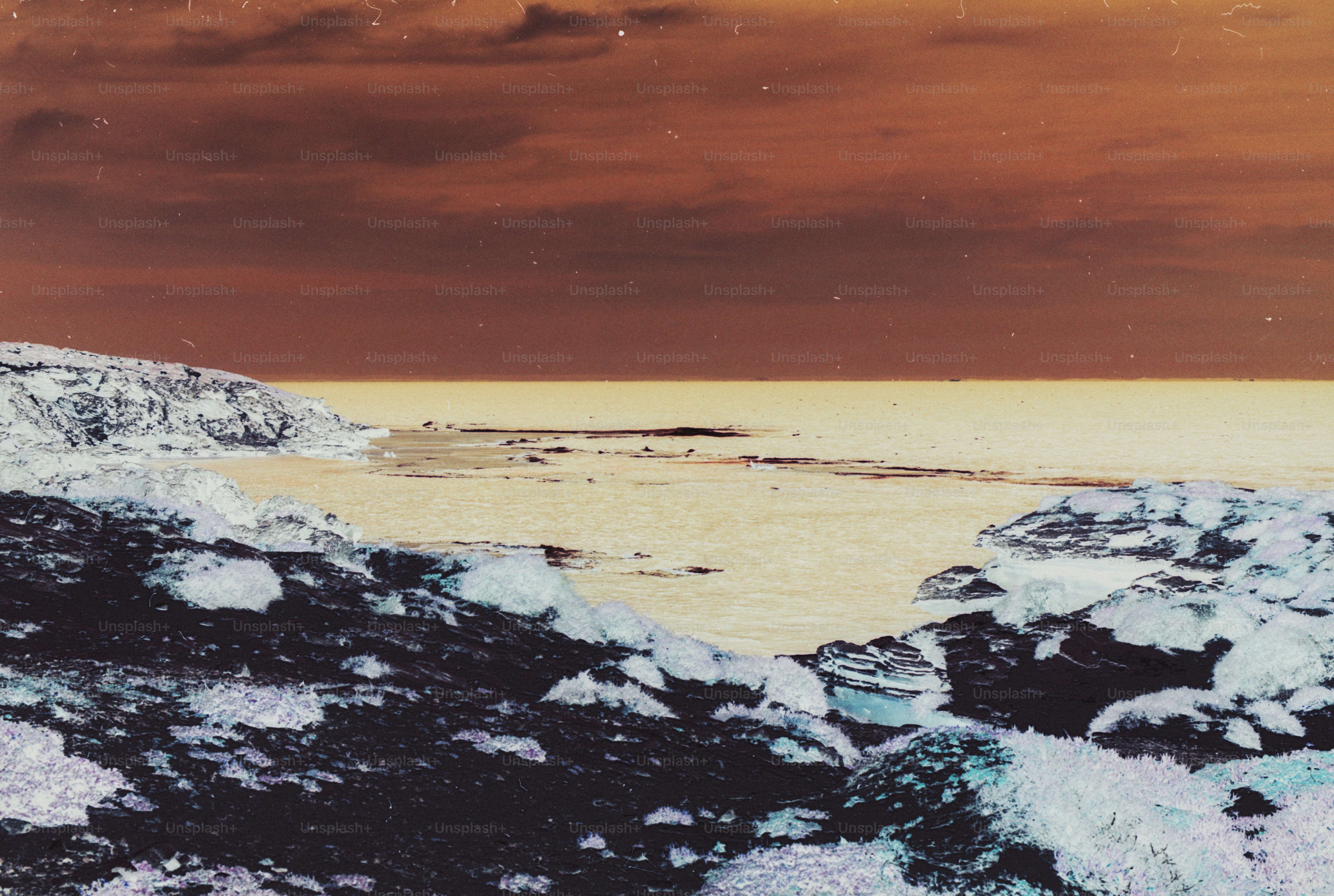 Inverted colors of a rocky coastline meeting a calm sea under a dark sky