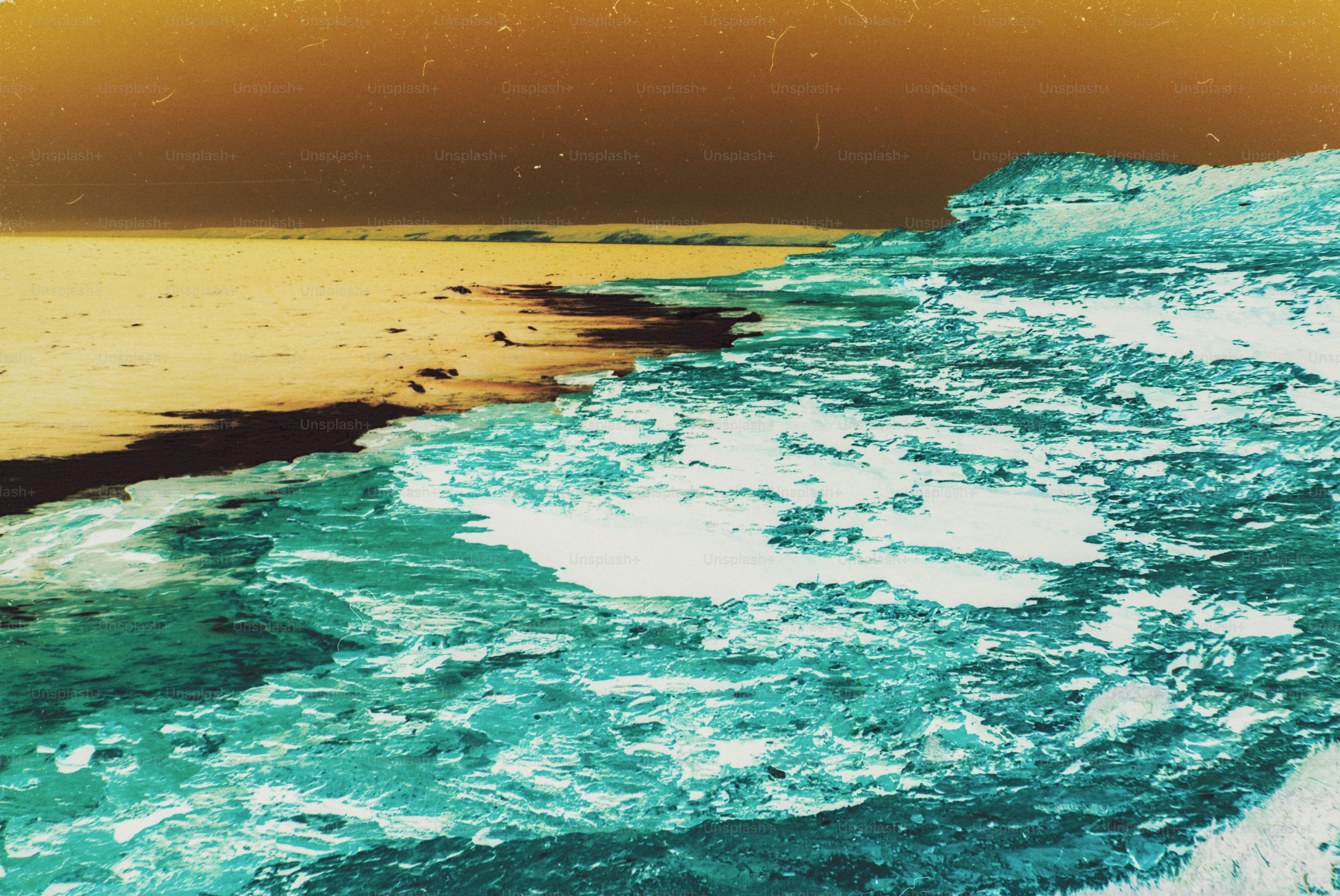 A turquoise rocky coastline meeting a golden sandy beach under a dark sky
