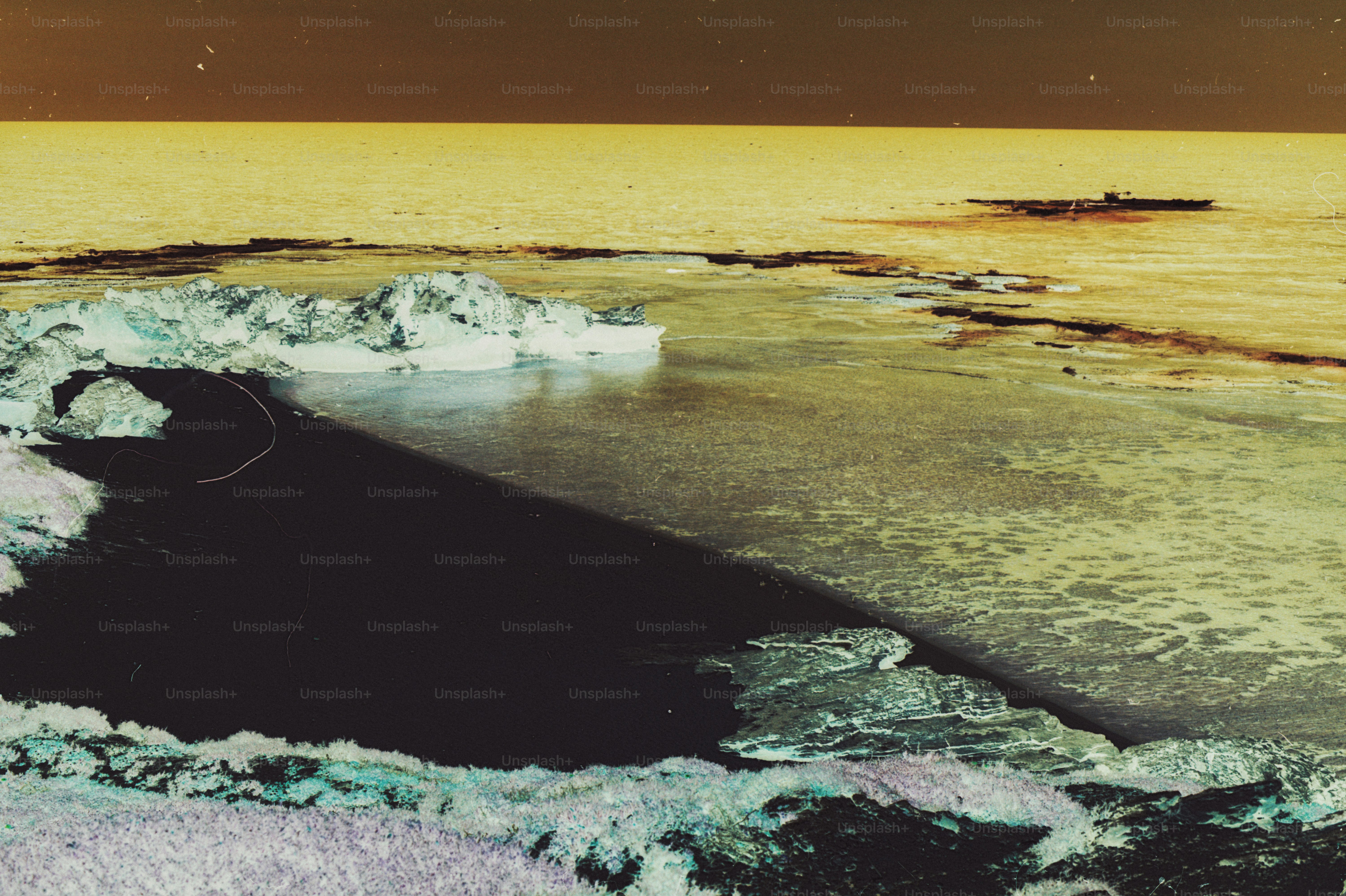 Inverted colors of ice chunks on a dark beach by a yellow sea