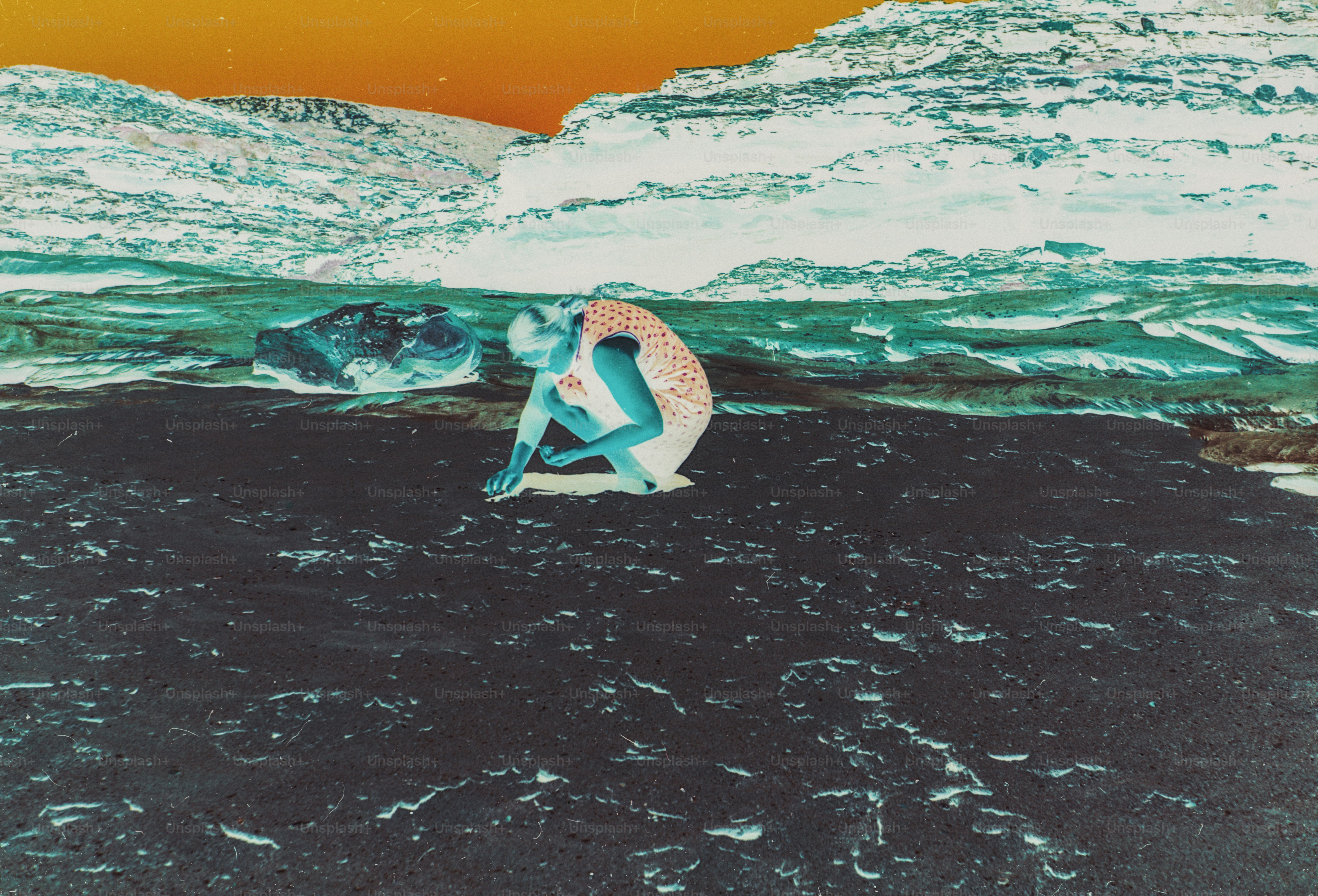 A person in a patterned dress crouching on a dark beach near rocky cliffs