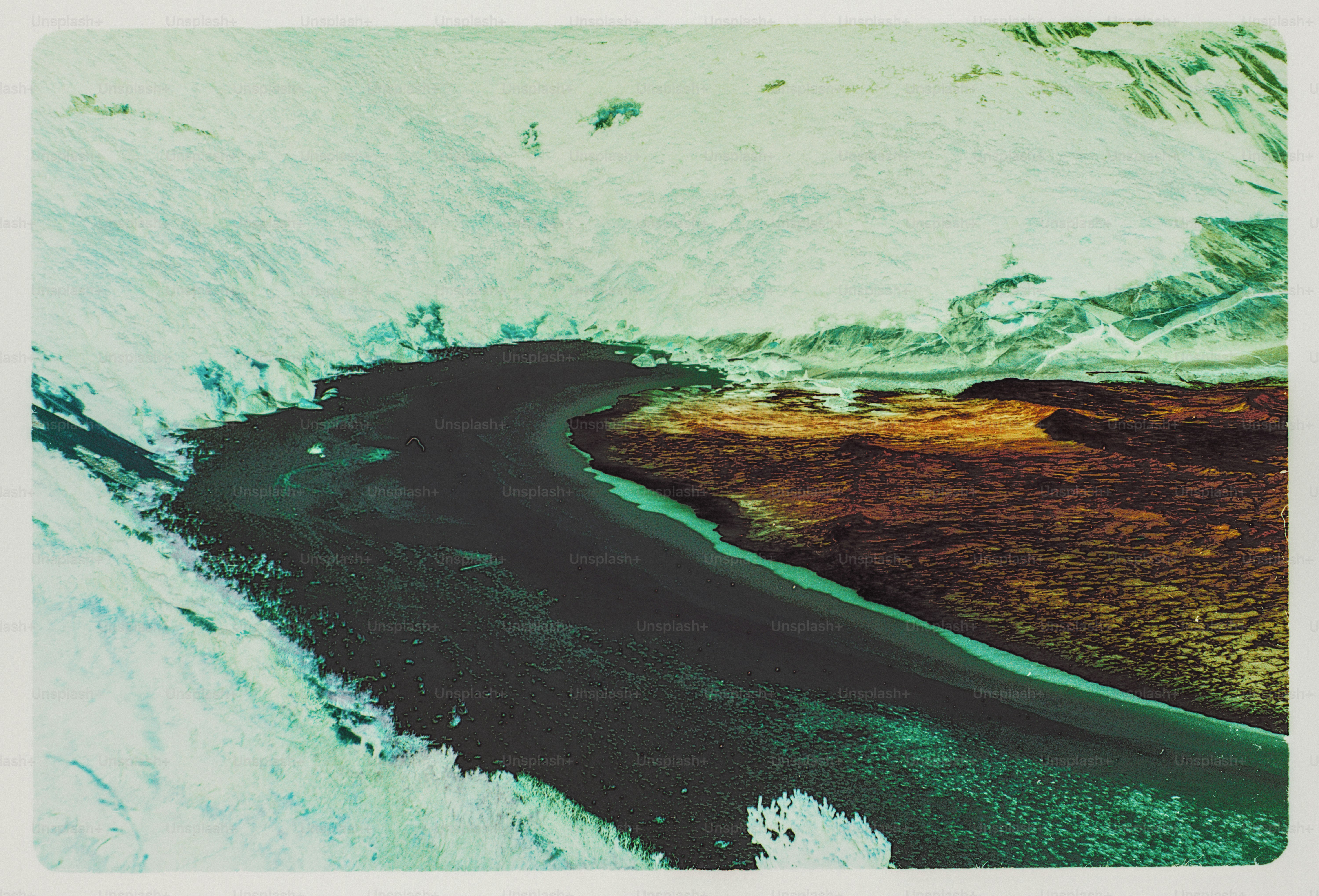 A dark river winding through a landscape of white snow and brown earth
