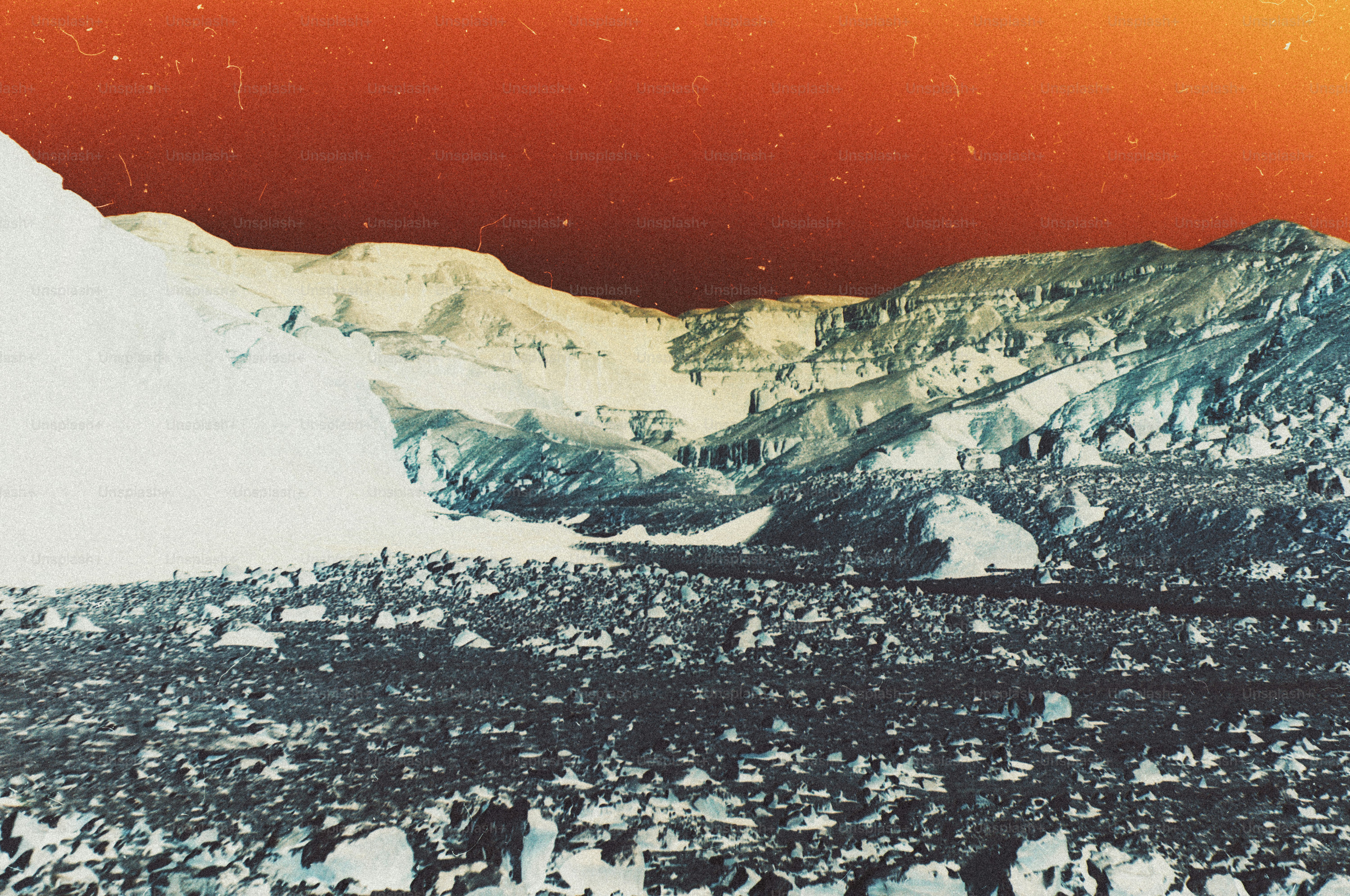A rocky landscape with a large glacier under a warm orange sky