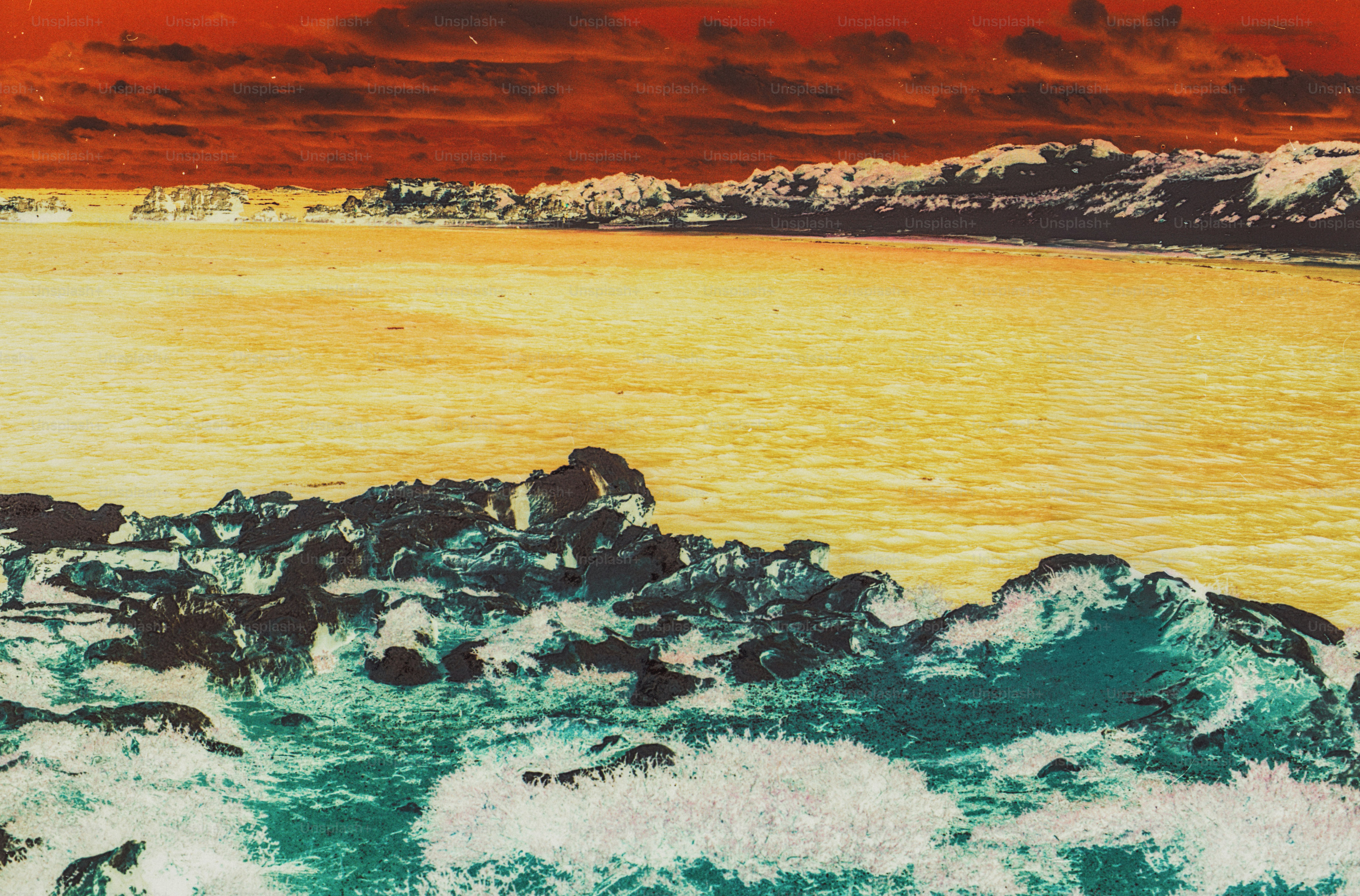Waves crashing against dark rocks with a yellow sea and red sky