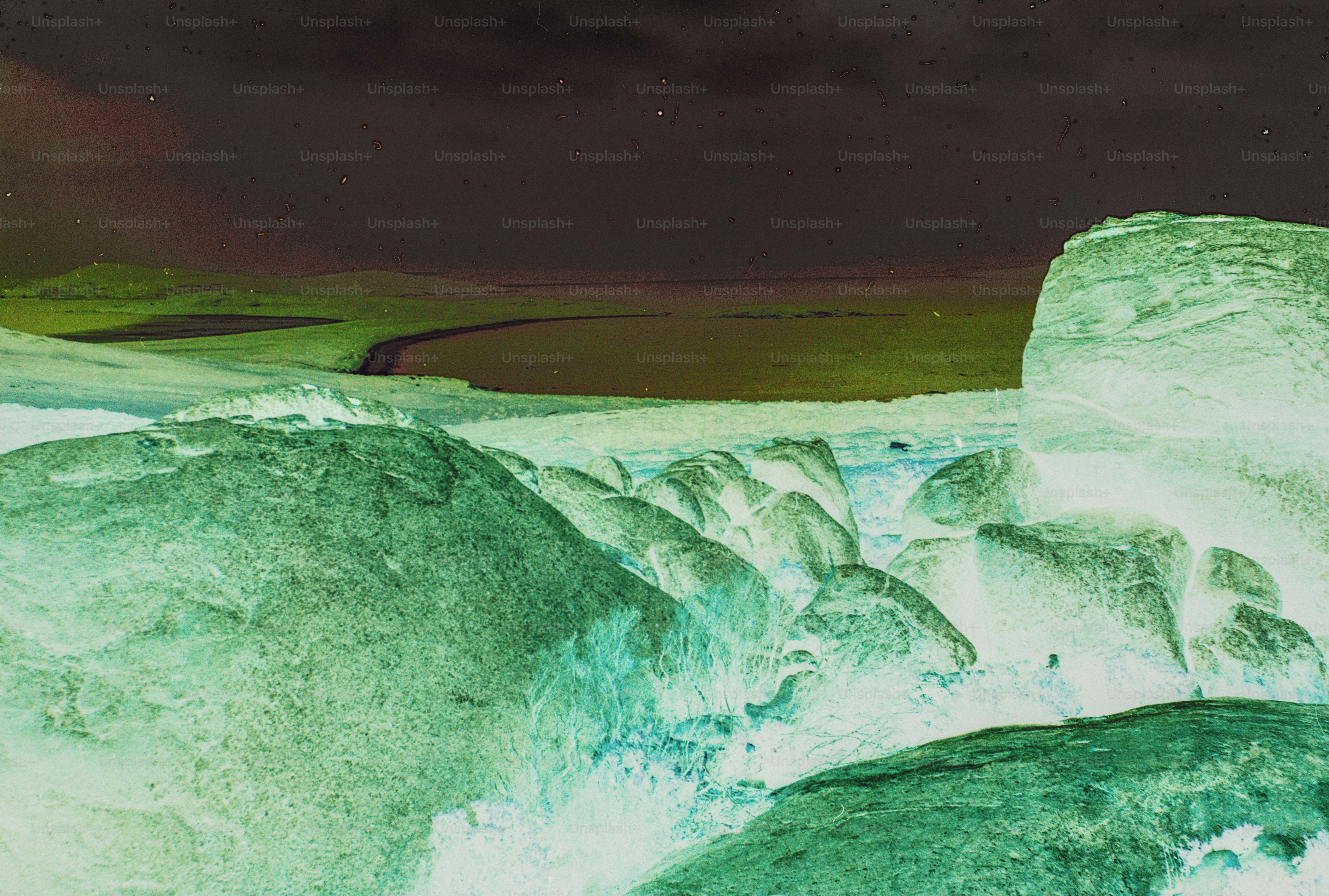 Large green rocks in a shallow stream under a dark, inverted sky