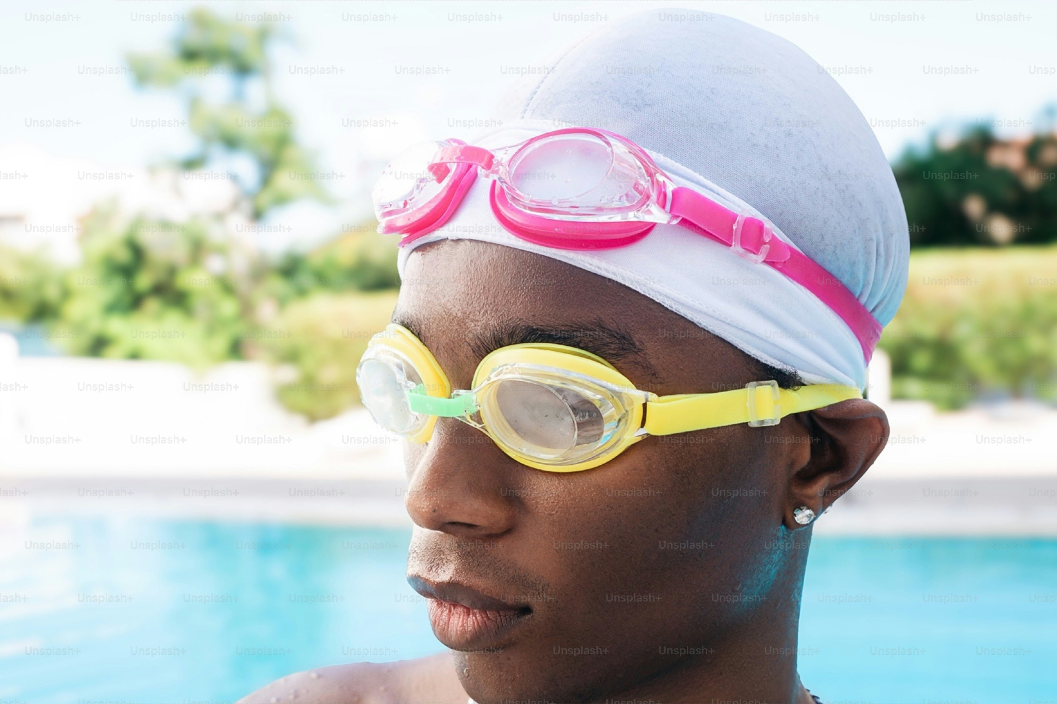 A person wearing a white swim cap and yellow goggles by a pool