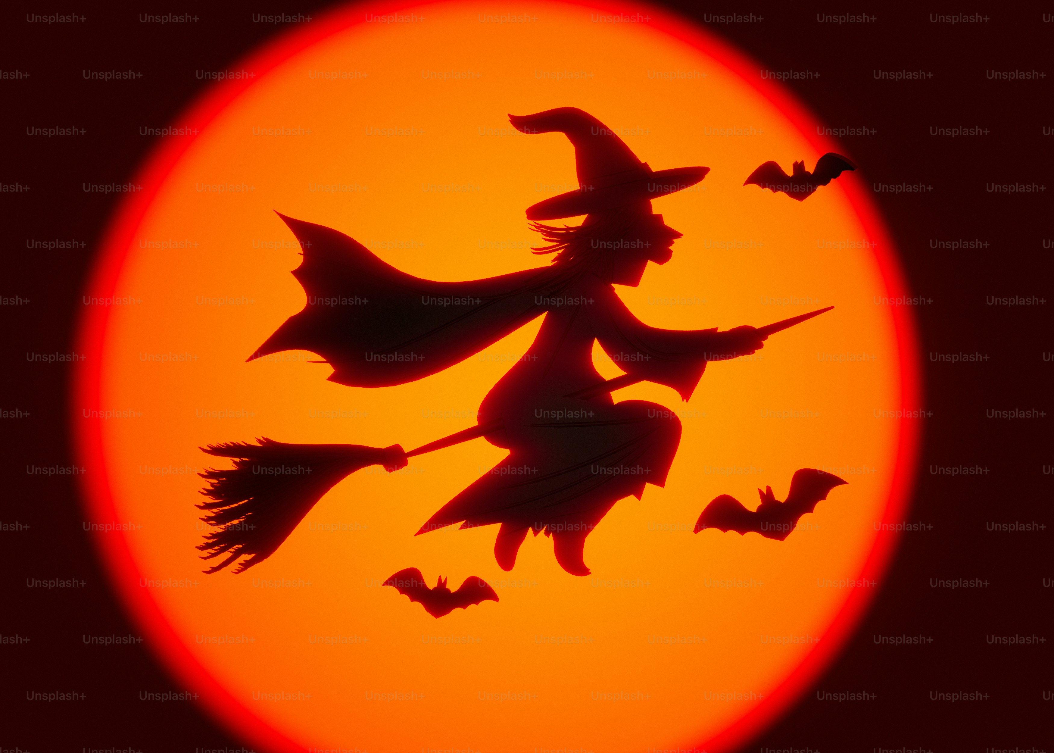 Eine Hexe in Silhouette, die auf einem Besen vor einem großen orangefarbenen Mond fliegt