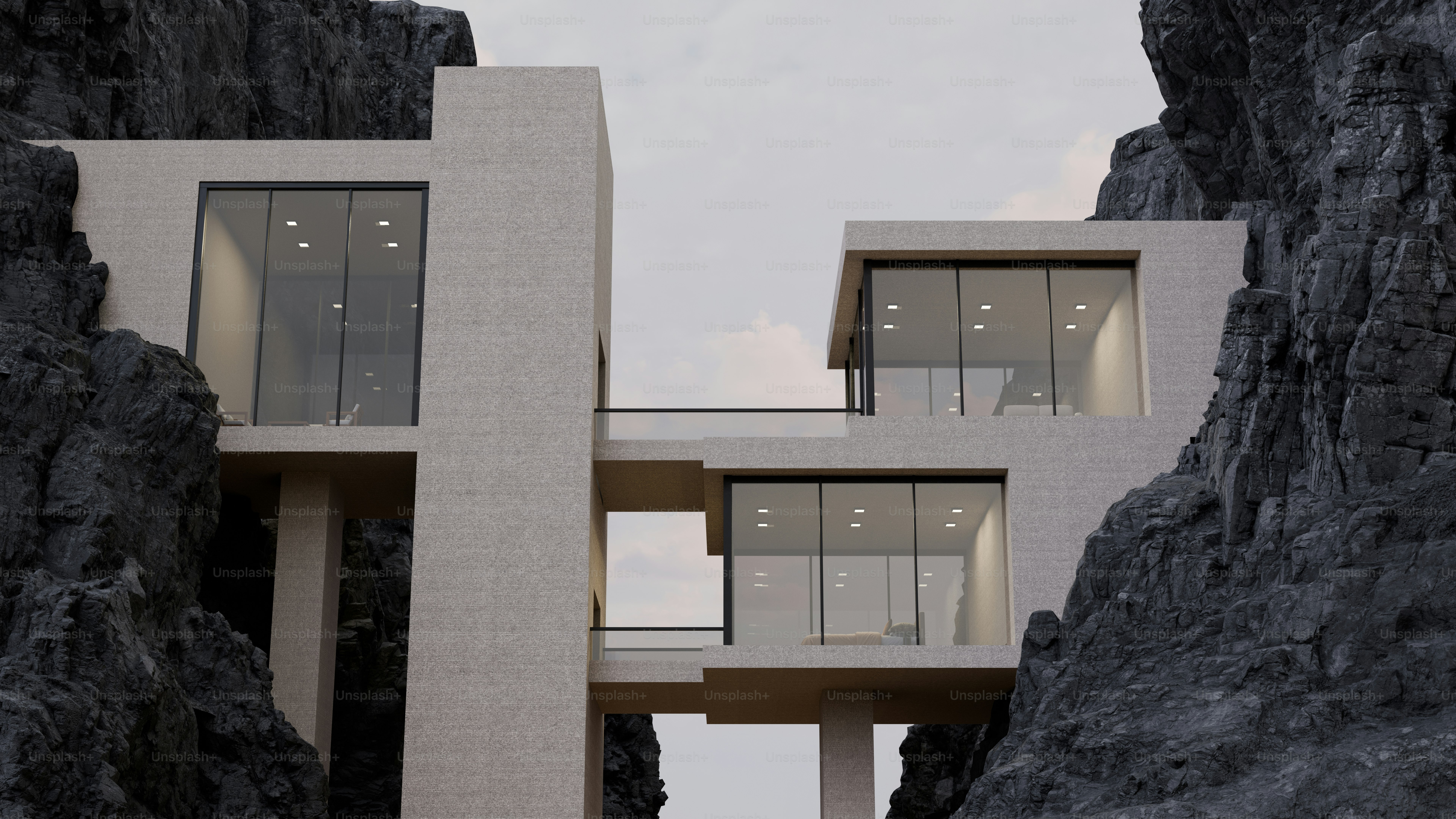A modern concrete house with glass walls nestled between two dark rocky cliffs