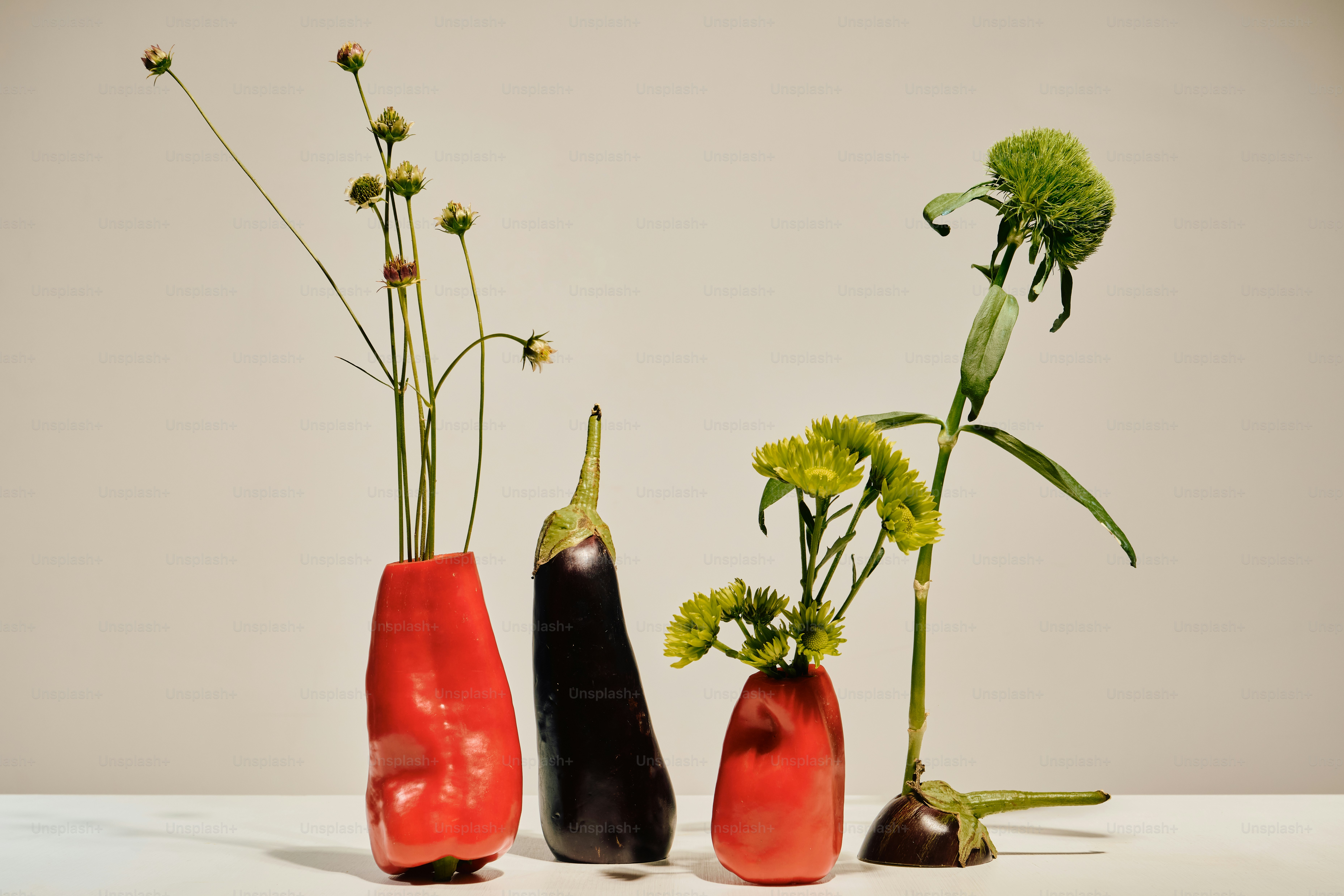 Wildflowers and green chrysanthemums in hollowed red peppers and eggplant on a table