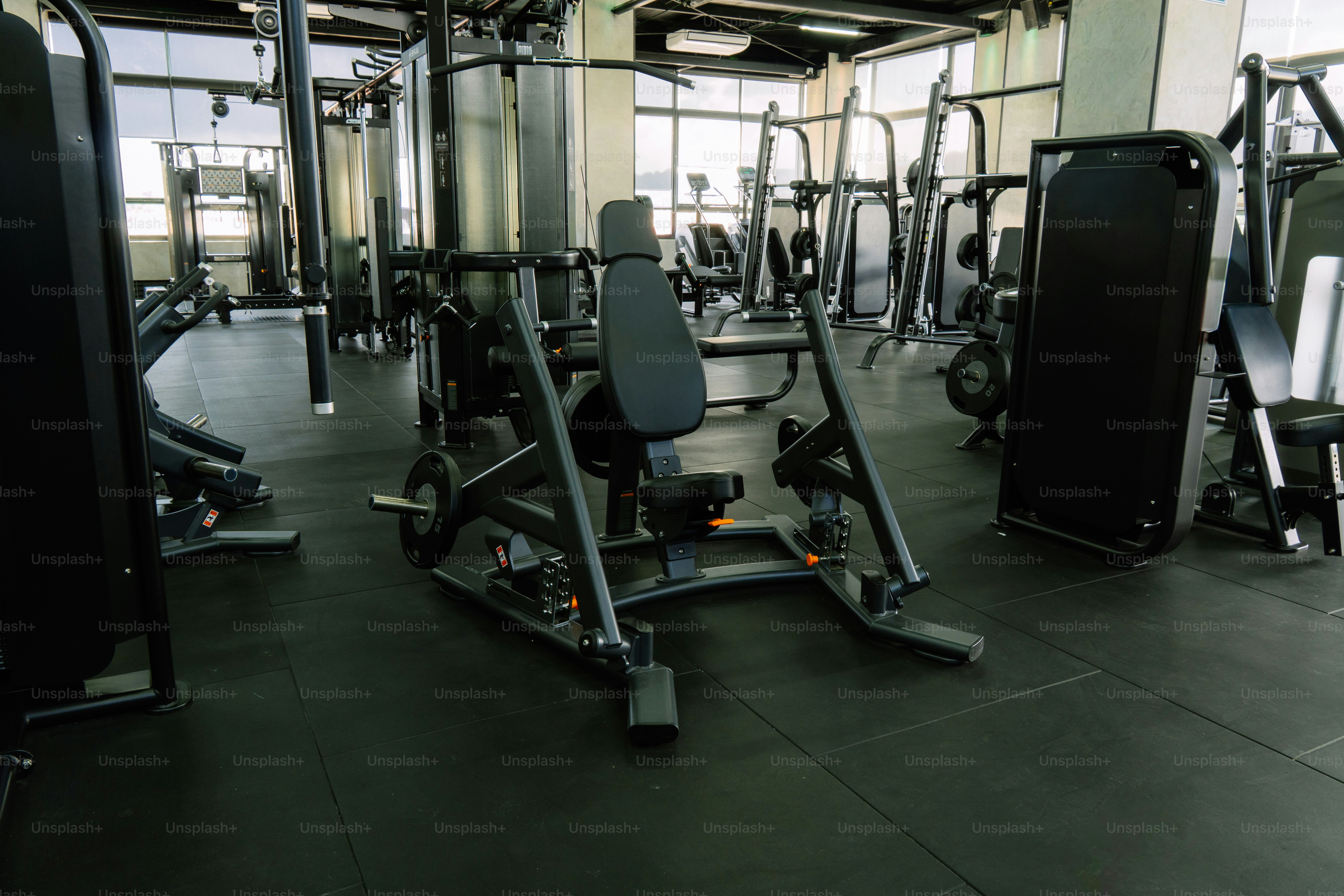 A variety of black weight machines arranged on a dark rubber gym floor