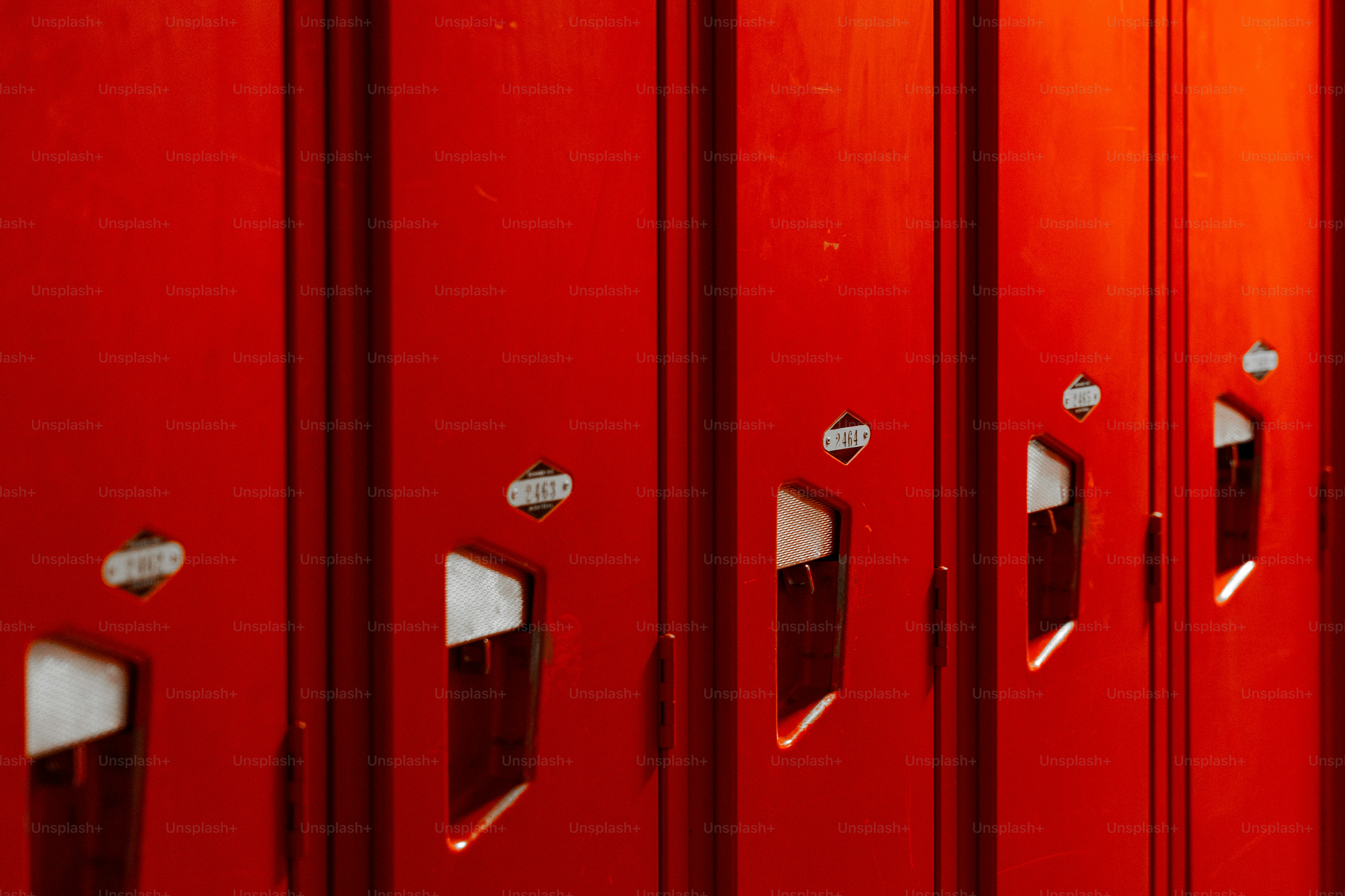 A row of bright red metal lockers with numbered identification tags