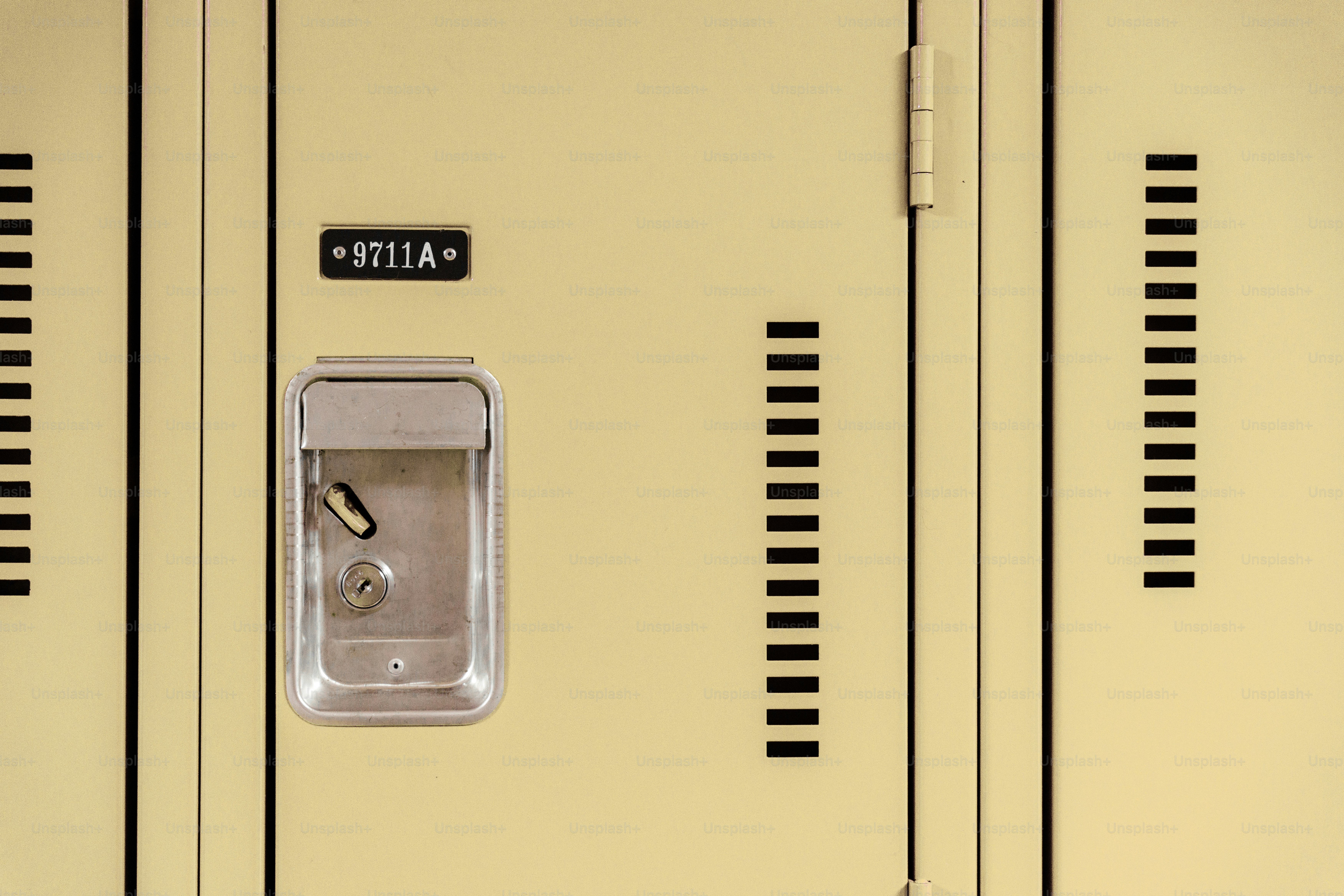 A beige metal locker with a silver handle and a plate reading 9711A