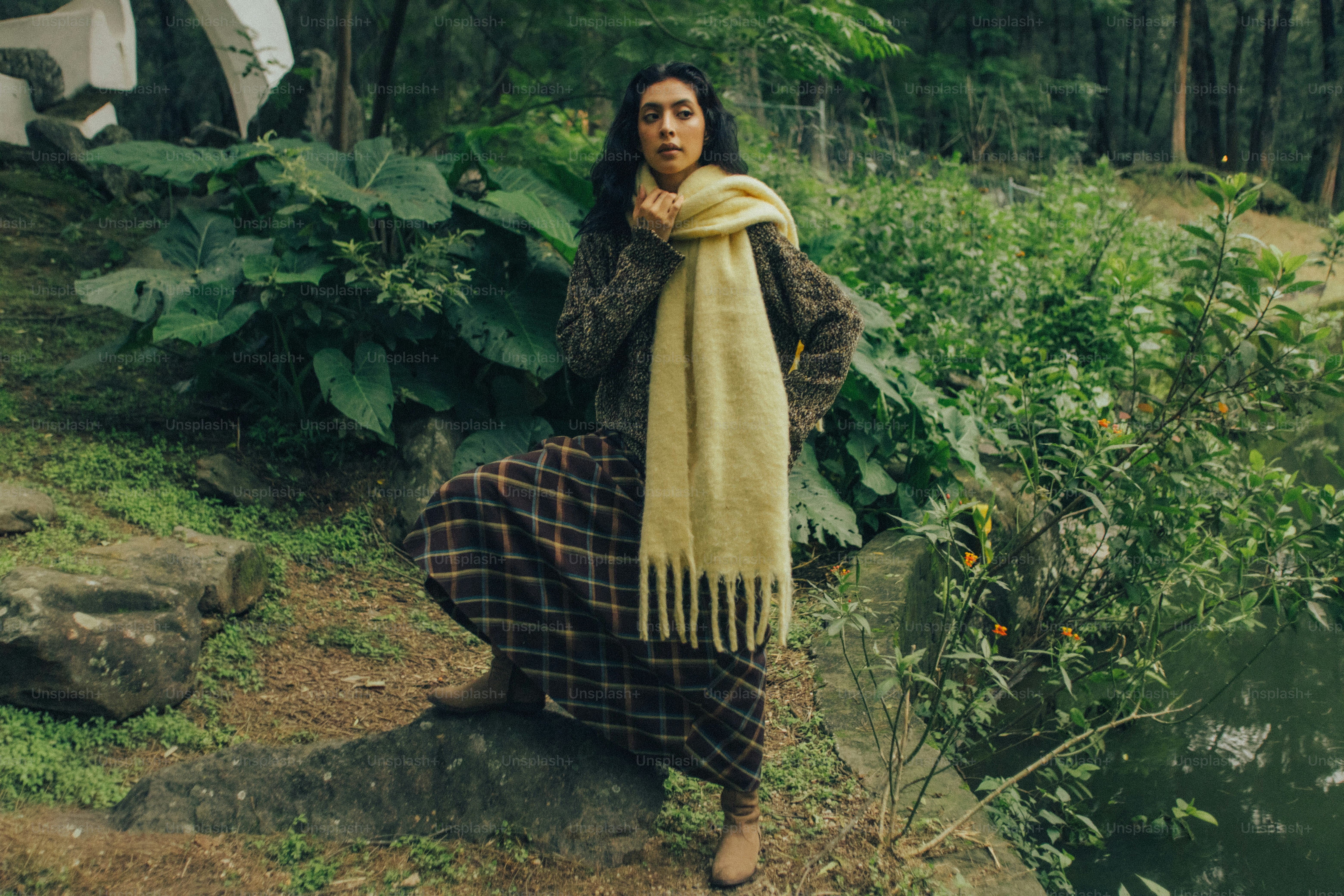 A woman in a plaid skirt and yellow scarf standing on a rock