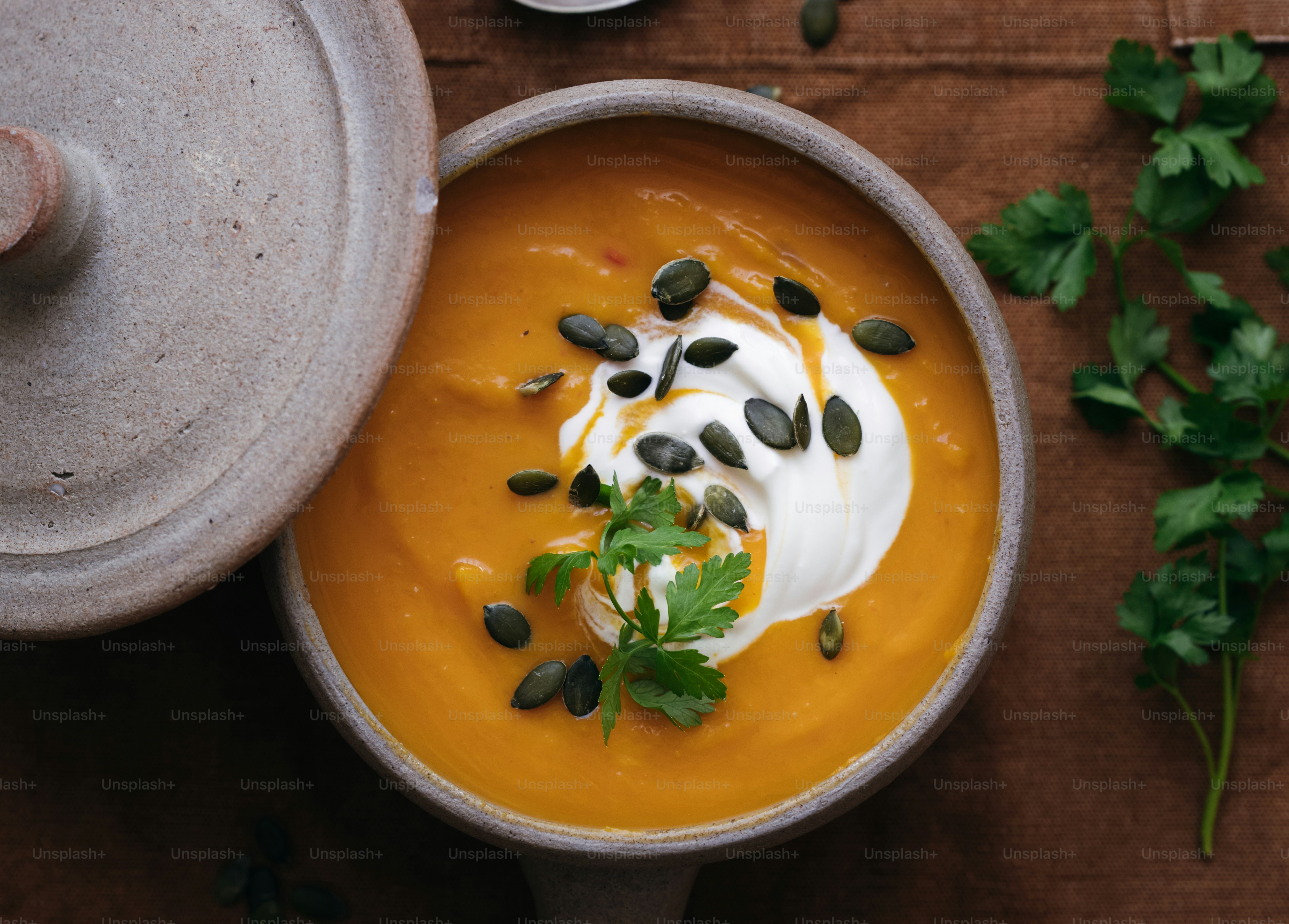 Un bol de soupe à l’orange garni de crème, de graines de citrouille et de persil frais