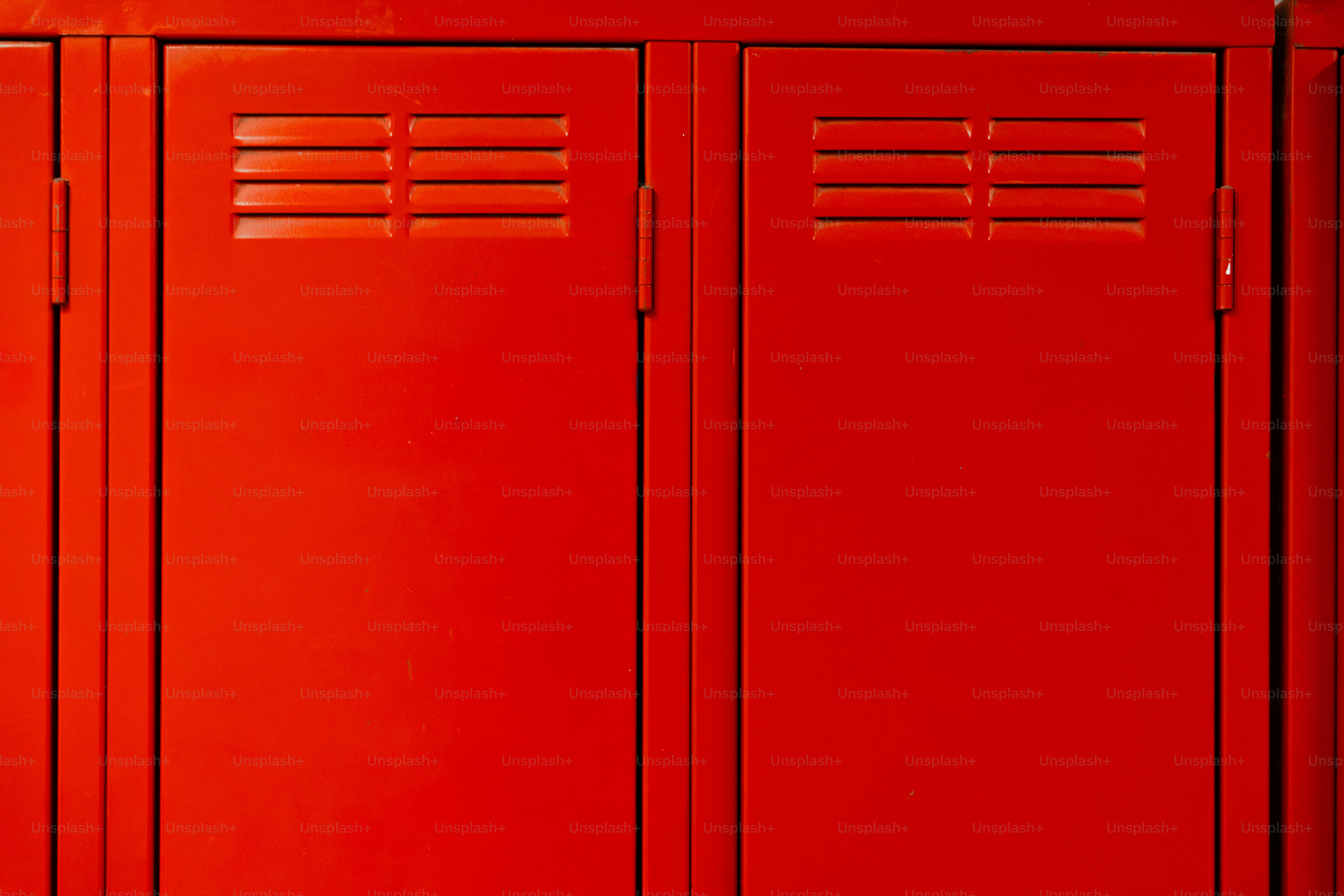 Two bright red metal lockers with horizontal ventilation slats in a row