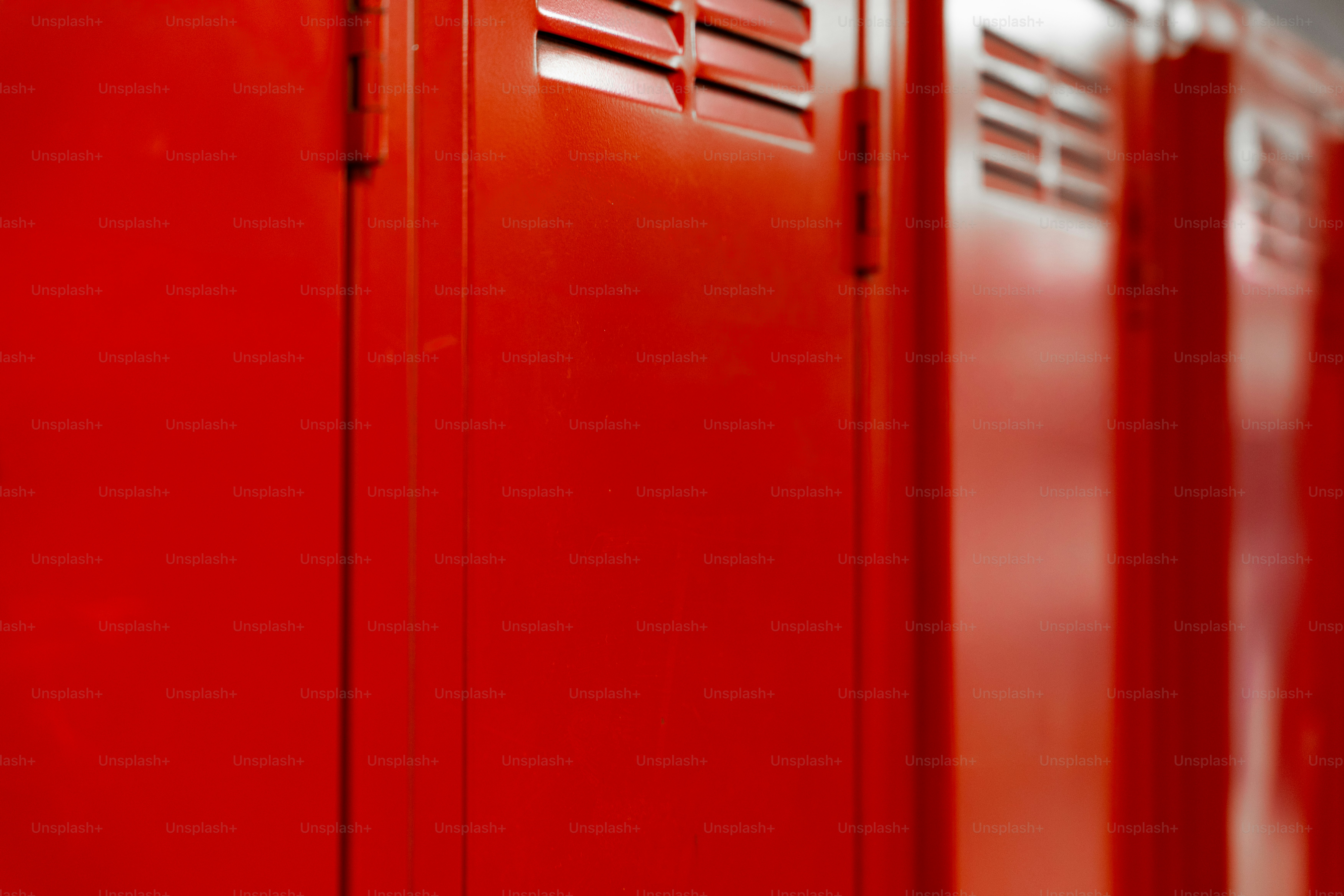 A row of bright red metal lockers with ventilation slats