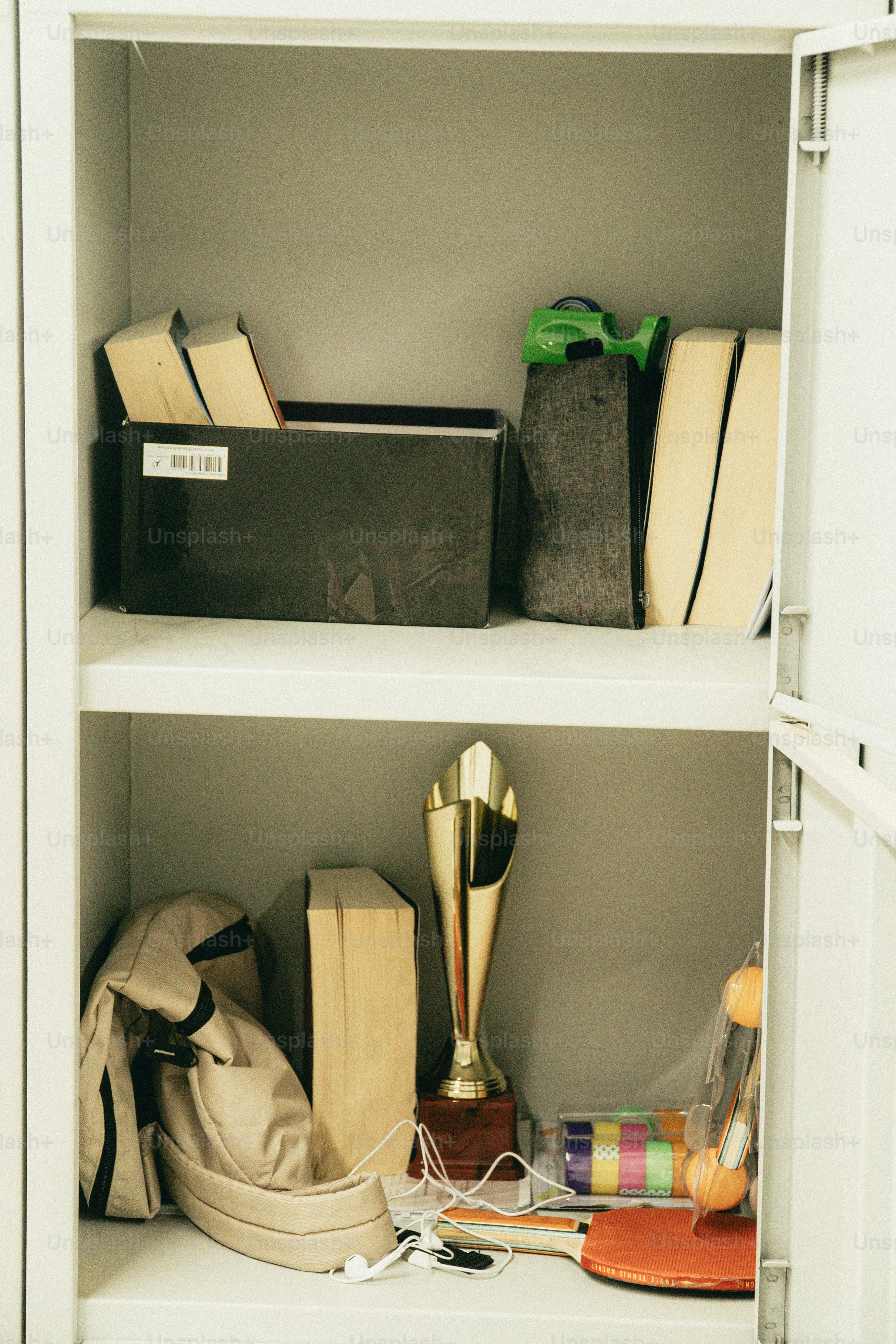 Books, a trophy, and a backpack inside a white metal school locker