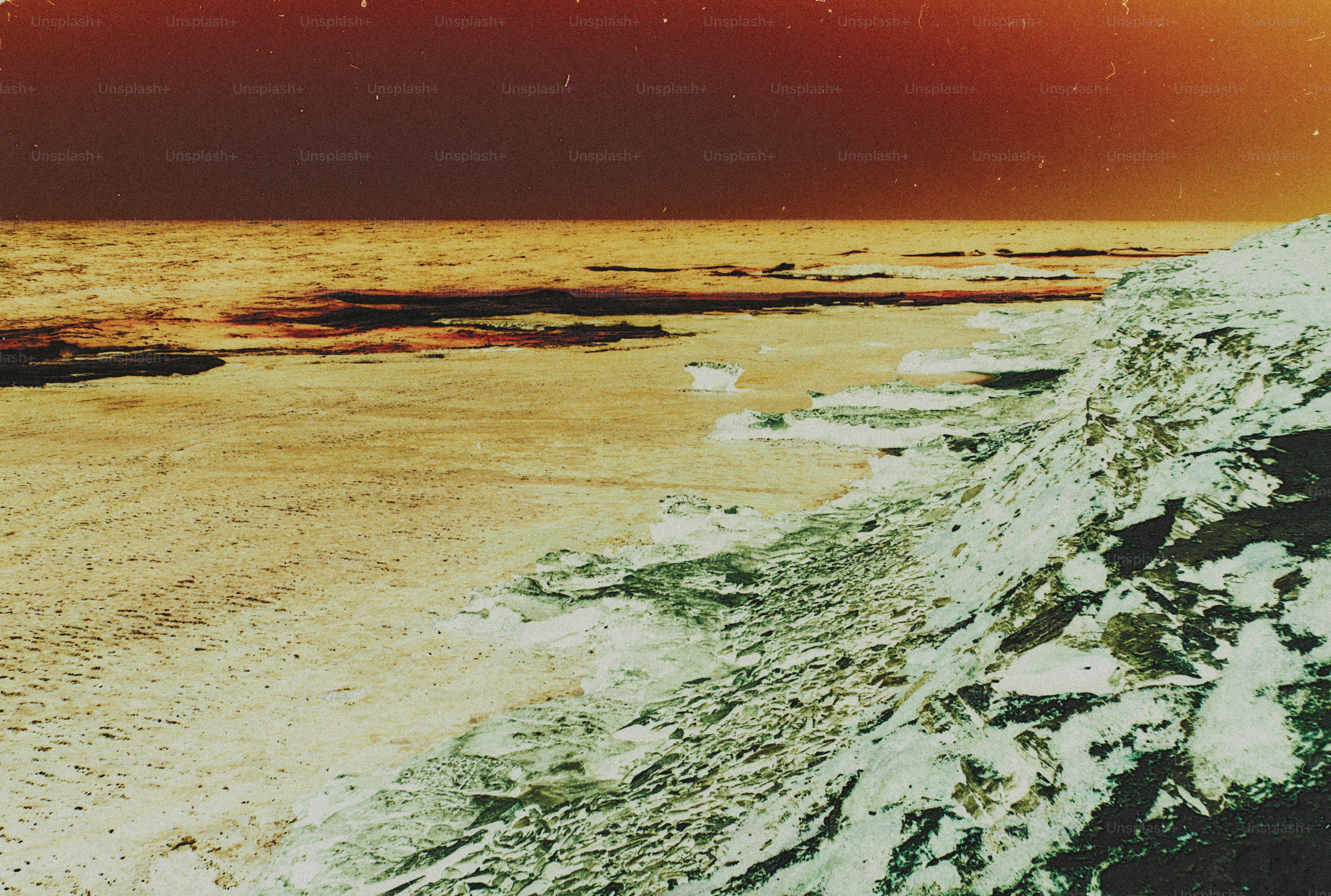A rocky coastline with textured cliffs meeting the sea under a dark orange sky