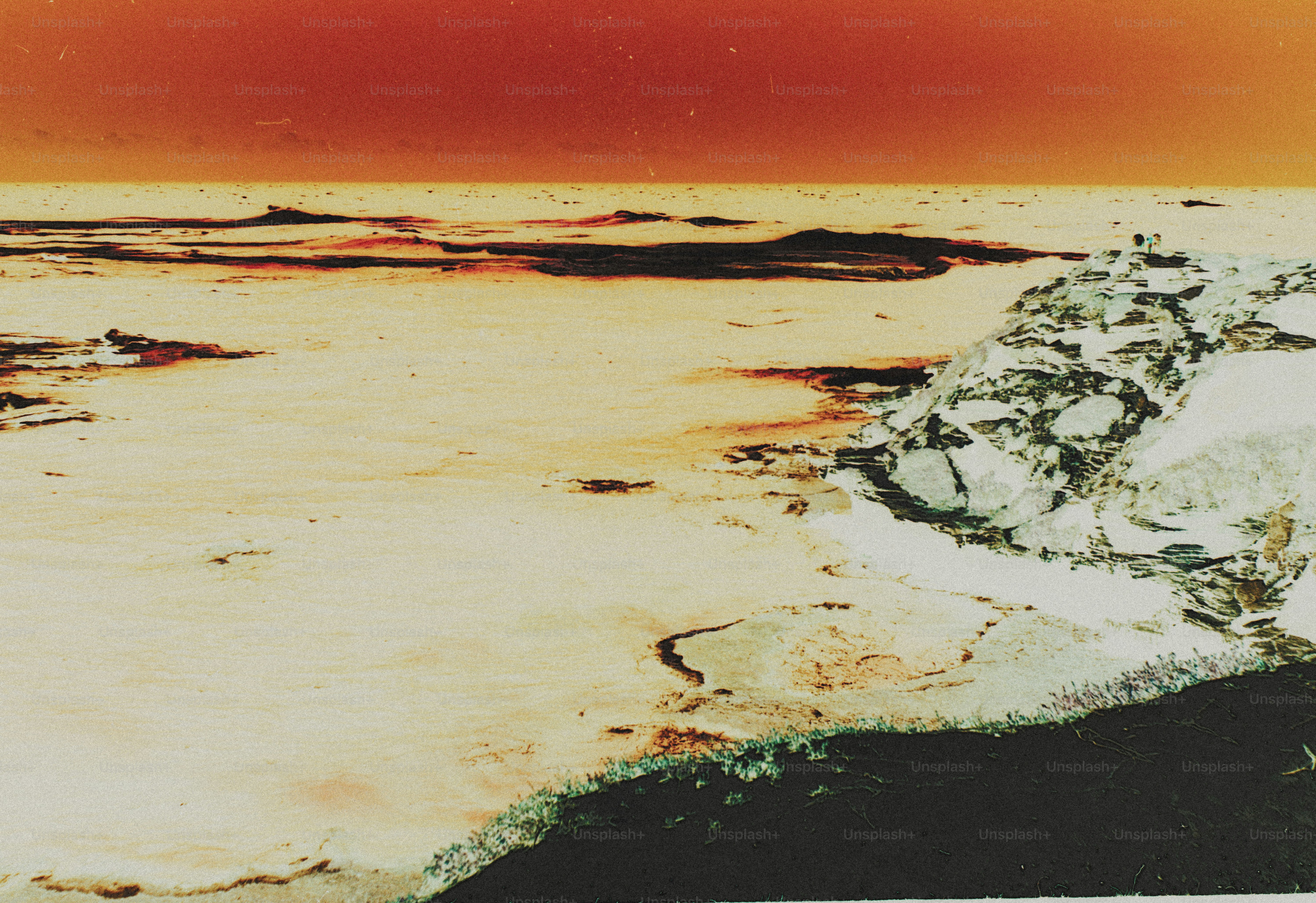 A person on a rocky cliff overlooking a vast expanse of water