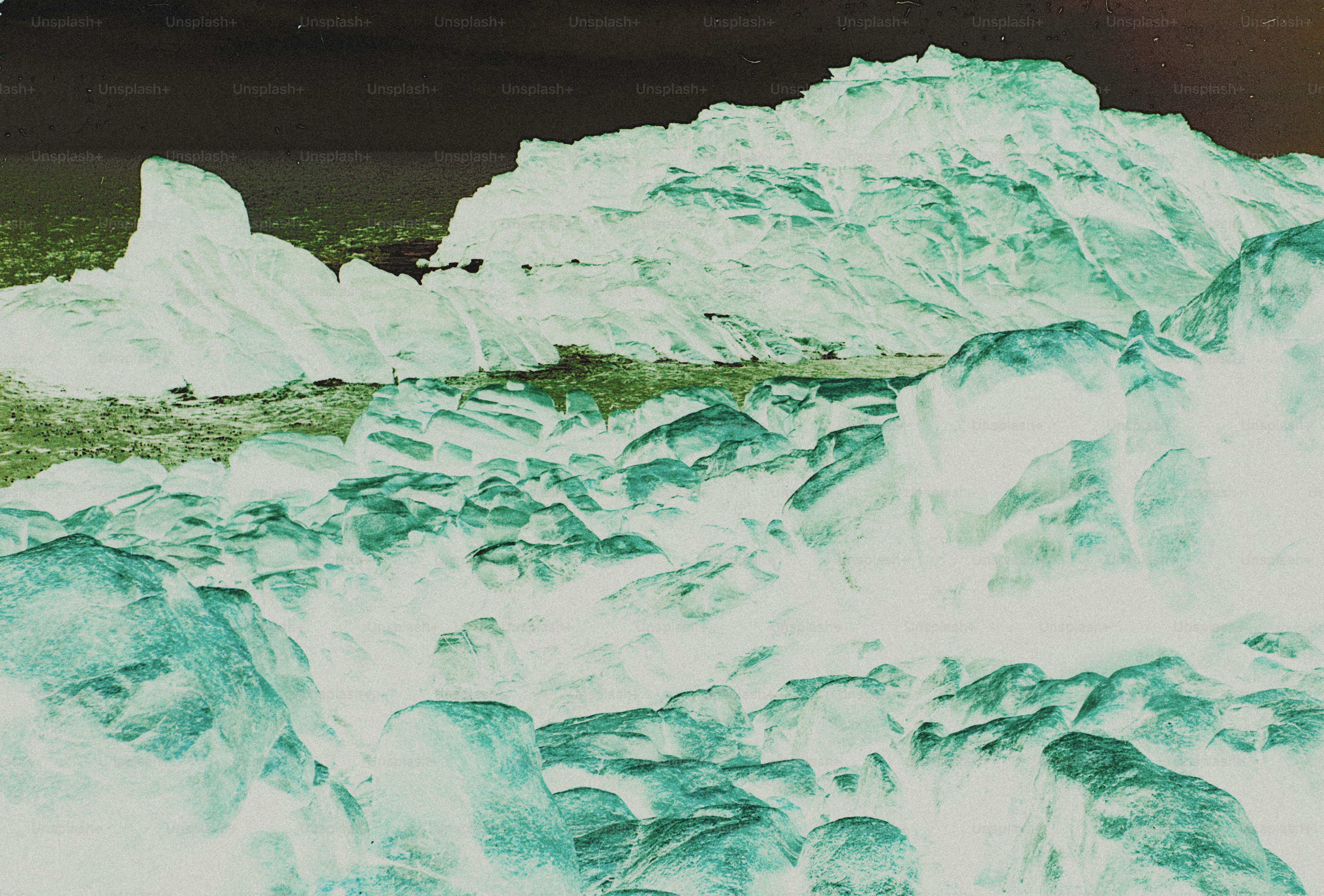 Inverted colors of a rocky coastline with large boulders and a distant hill