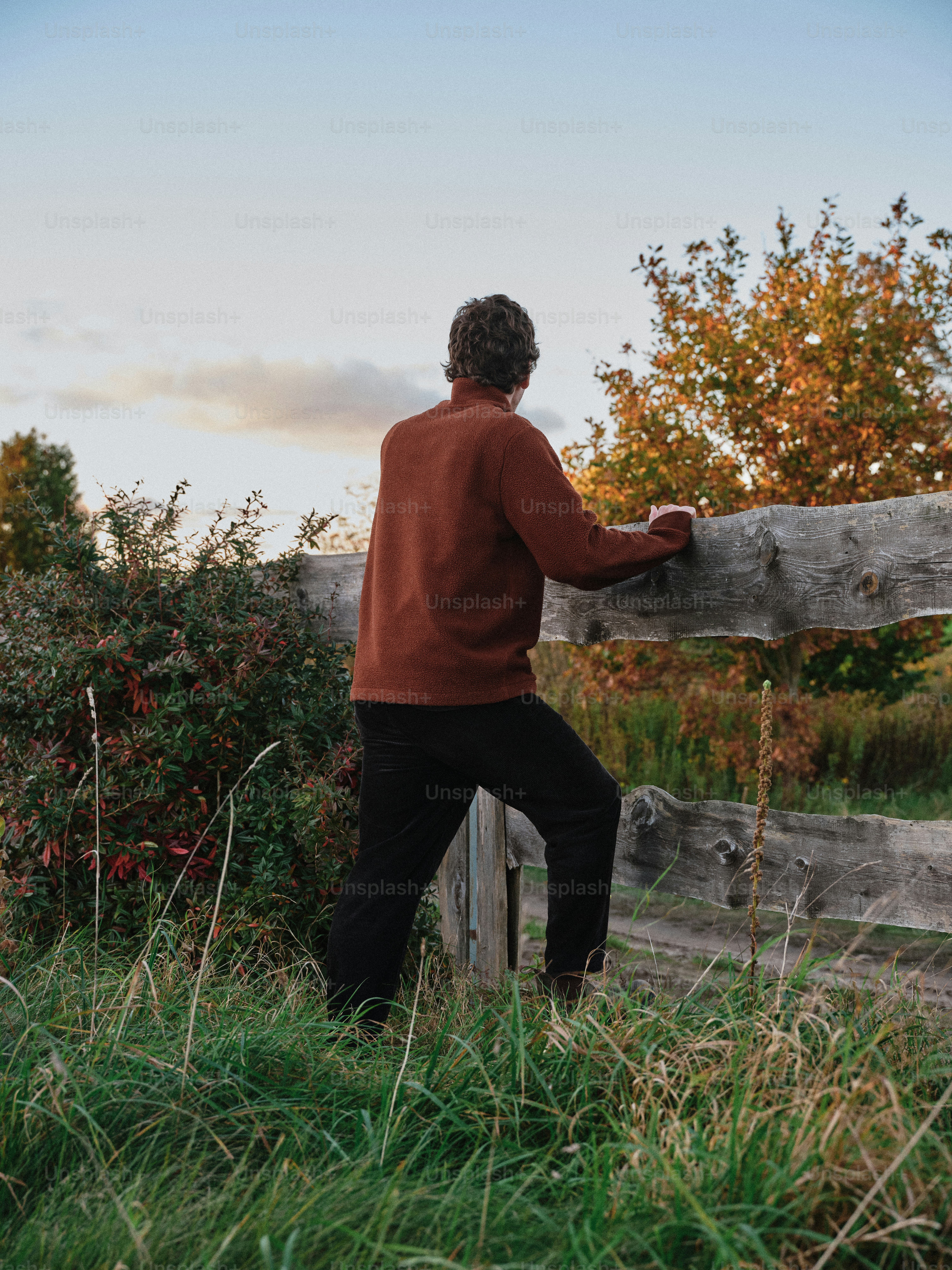 Person in cream sweater leaning on fence - Photo on Unsplash+