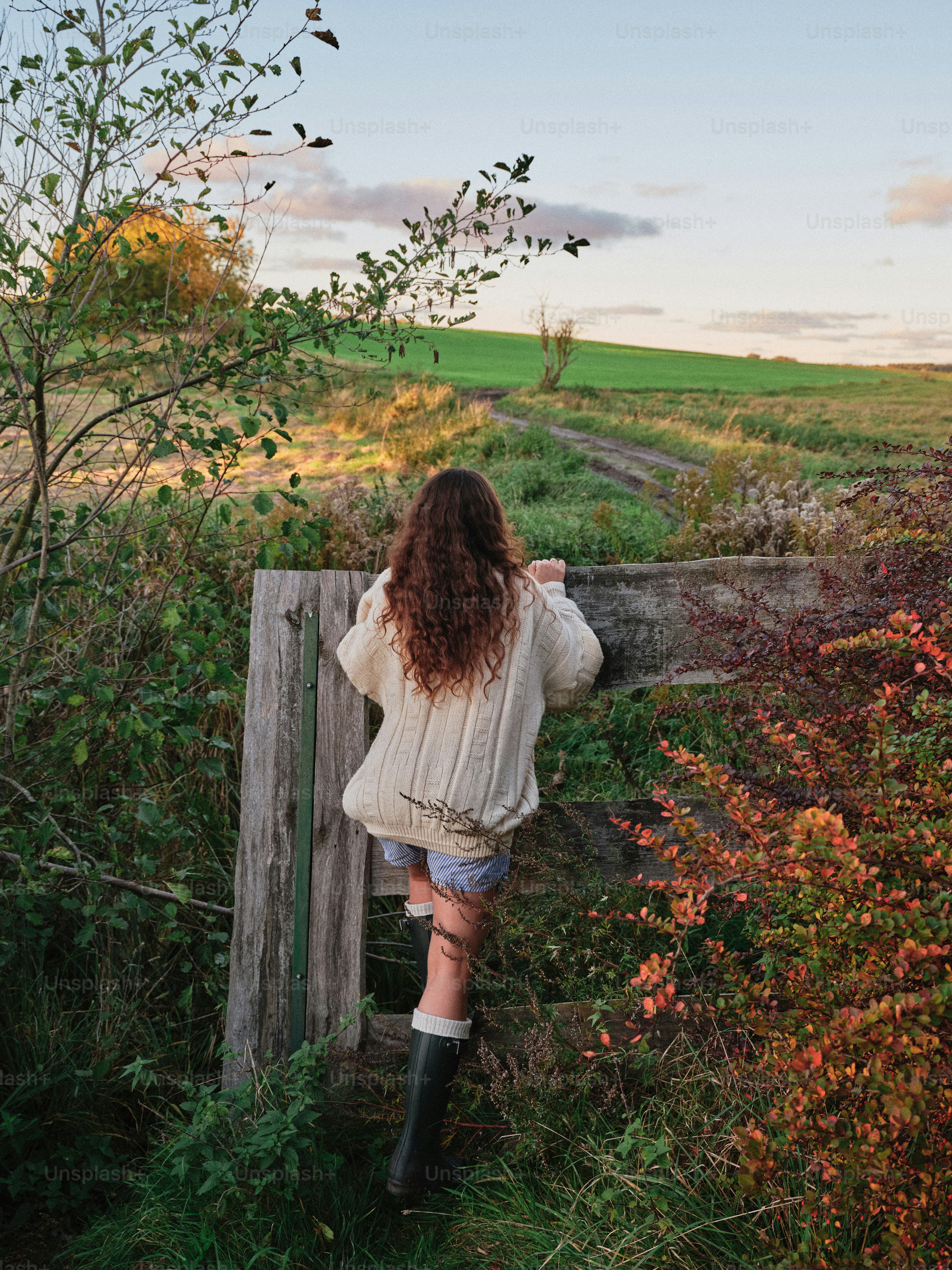 Person in cream sweater leaning on fence - Photo on Unsplash+