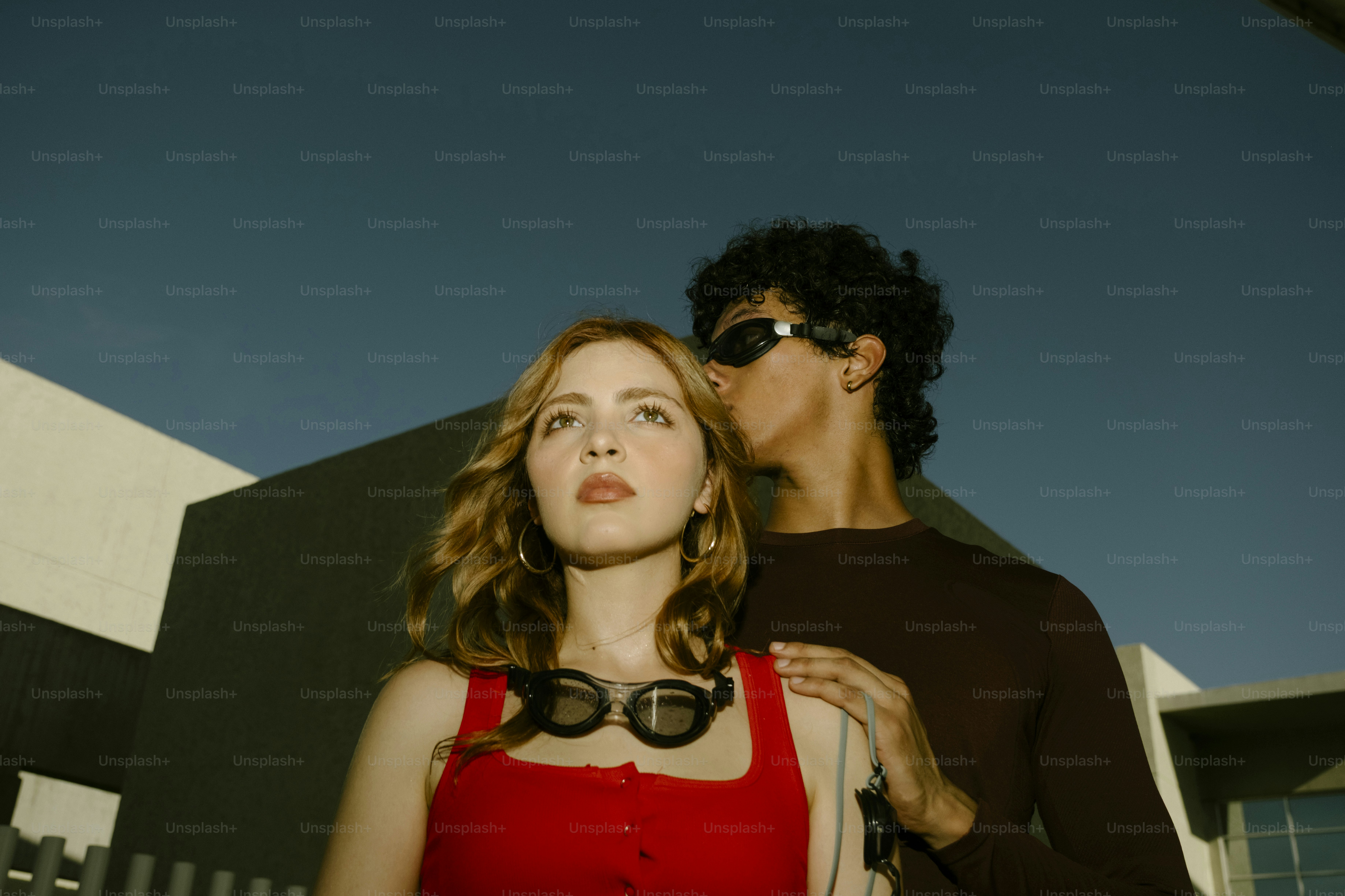 A woman in a red top and a man wearing swim goggles outdoors