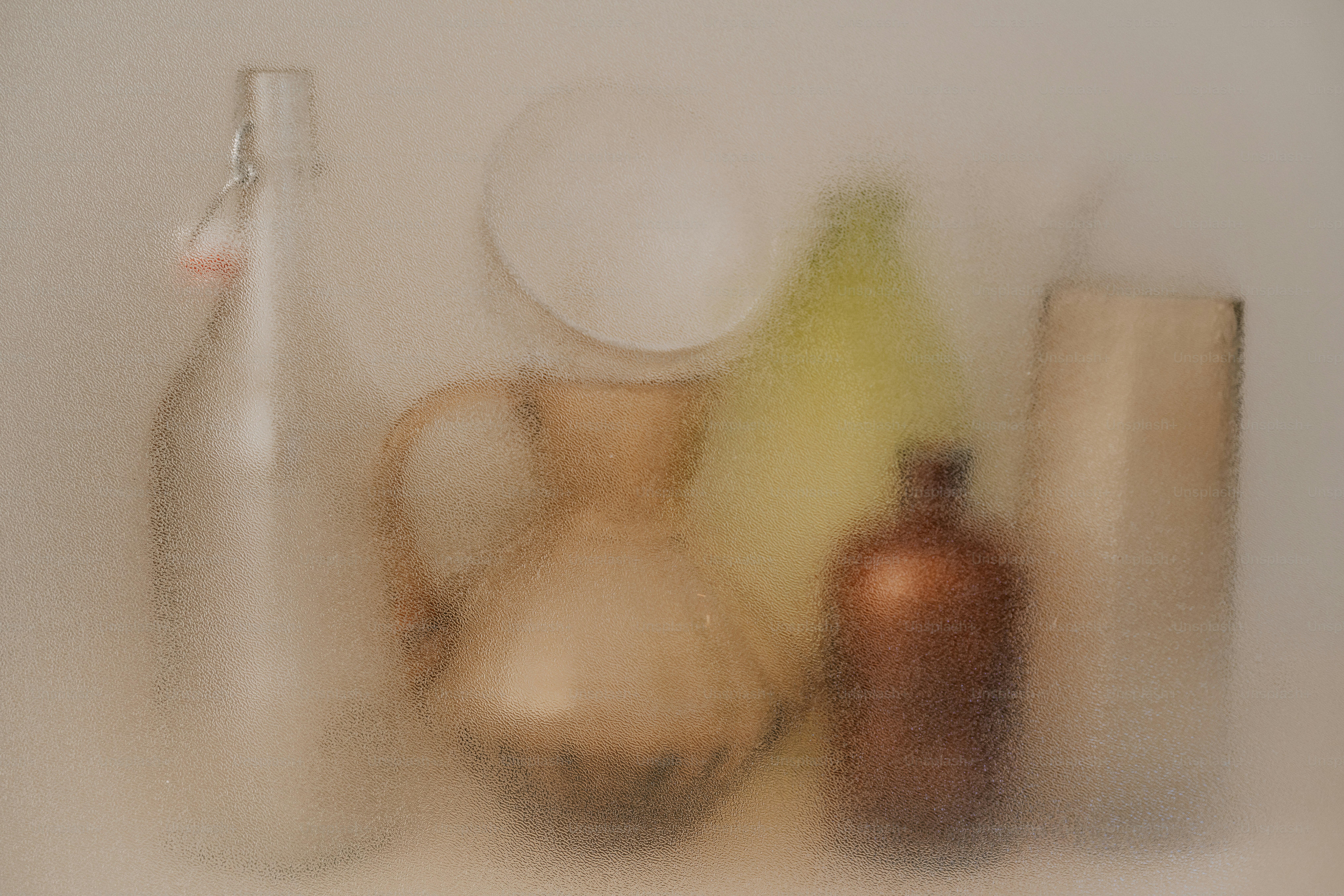 Glass bottles and a pitcher viewed through a textured frosted glass surface